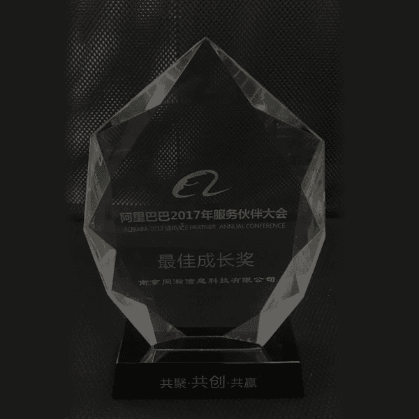 A modern hallway features vibrant teal and orange geometric and leaf patterns, with glossy tiled floors, a large rectangular light fixture, and a small shelf holding a potted plant, all leading to a large, frosted window at the end.