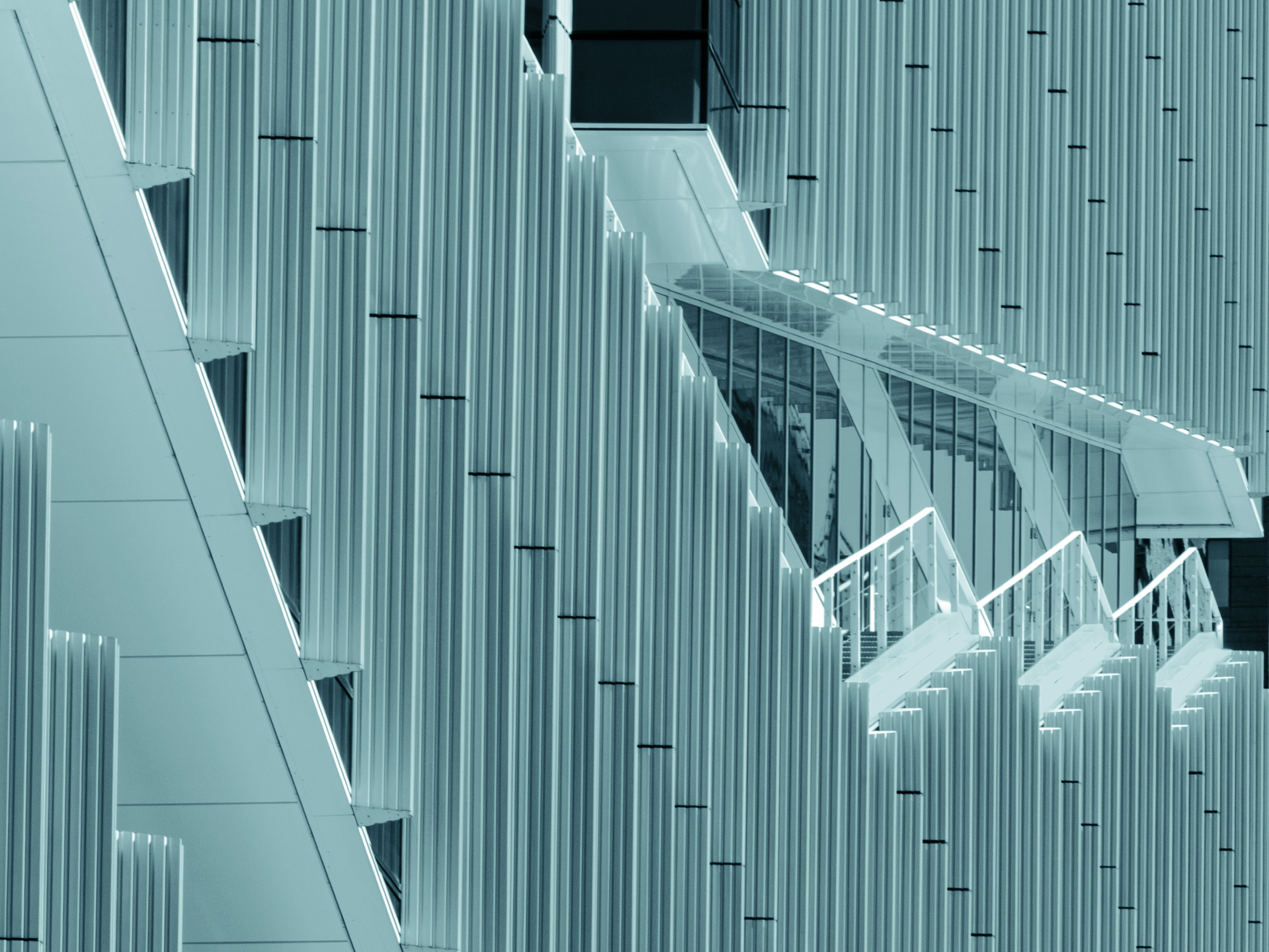 Modern building facade with vertical fins and a glass walkway.