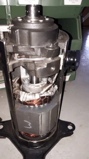 Detailní záběr motoru s odříznutou částí, který ukazuje vnitřní součásti, jako jsou měděné vodiče, kovové části a centrální hřídel.