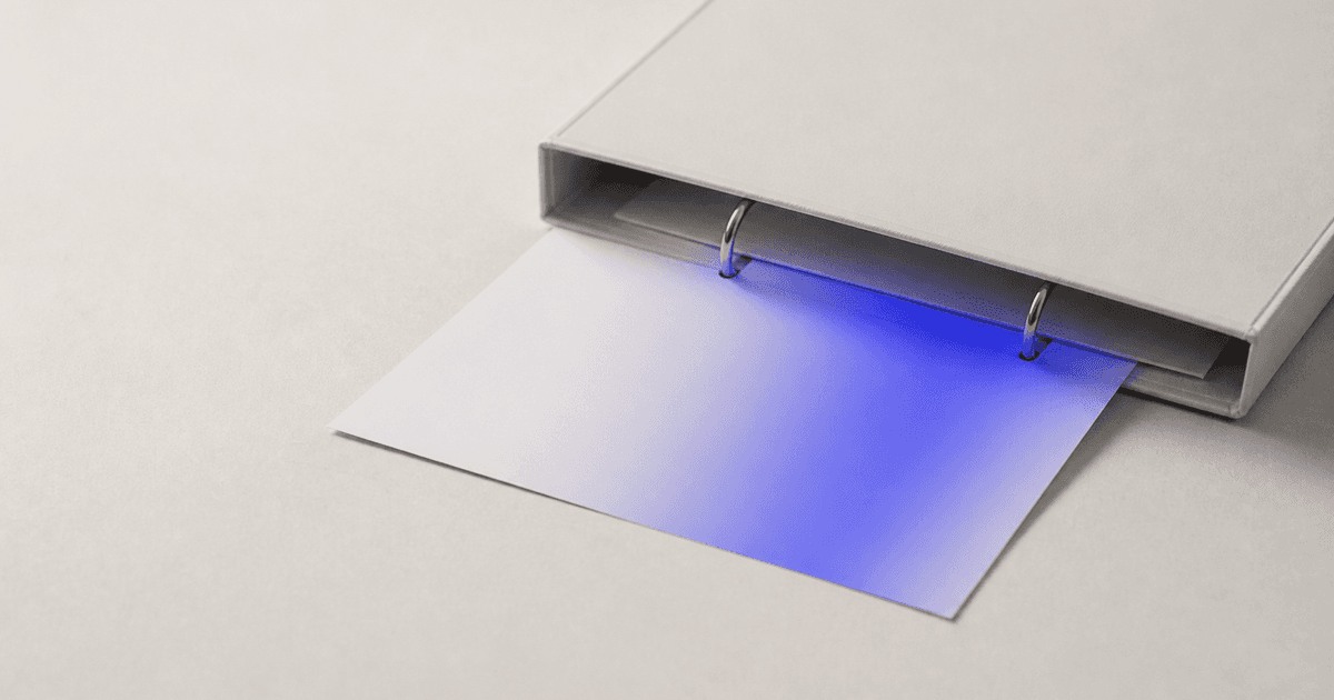 An invoice sheet slides beneath the open edge of a ring binder.