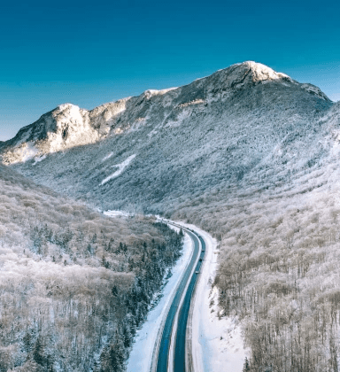 Snow-covered rural road curving through mountains