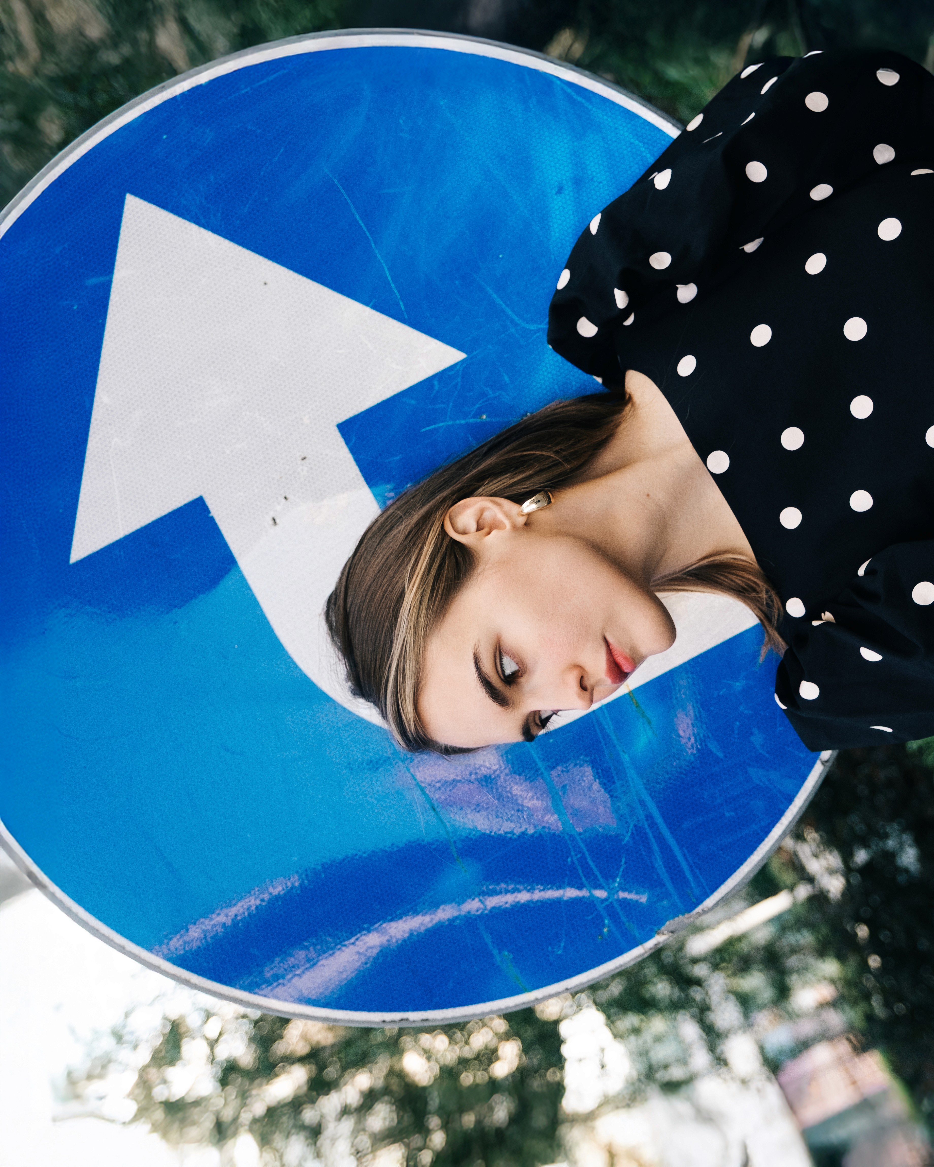 Ania – She Owns the City - leaning her head against a blue road sign.