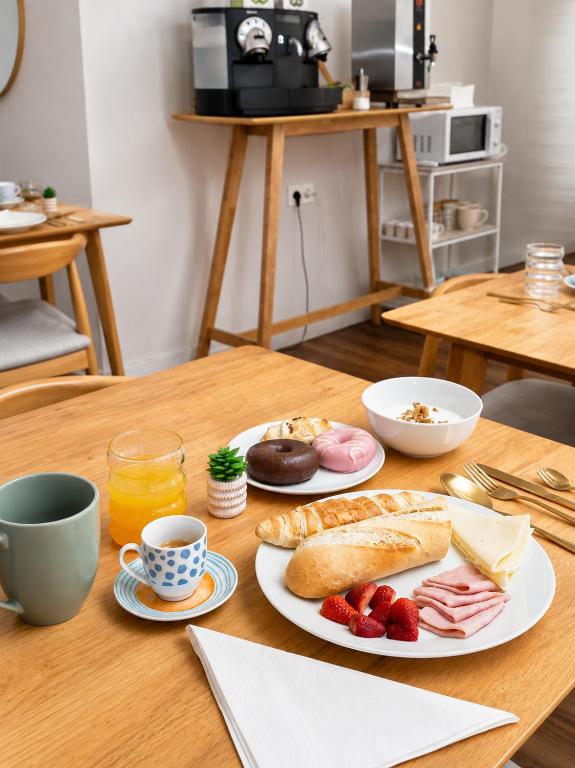 Casa Jazmín Granada: Breakfast spread on a wood table with coffee, juice, bread and pastries