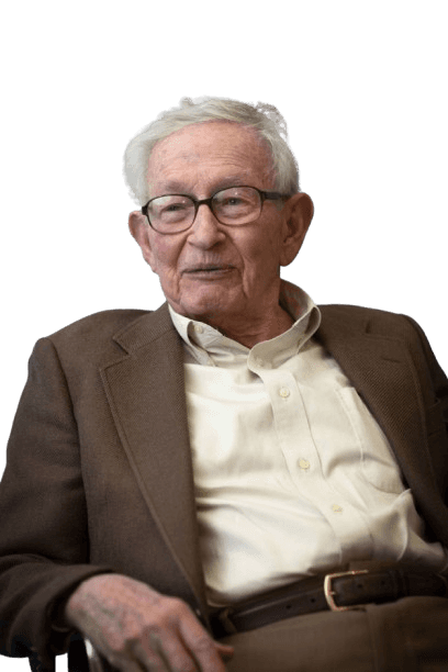 Renowned physicist and Nobel laureate Leon Cooper is shown in this candid portrait, wearing glasses, a light-colored shirt, and a brown blazer, with a relaxed expression. Cooper is celebrated for his work on superconductivity and for co-developing the BCS theory, which explains the behavior of superconductors at low temperatures.