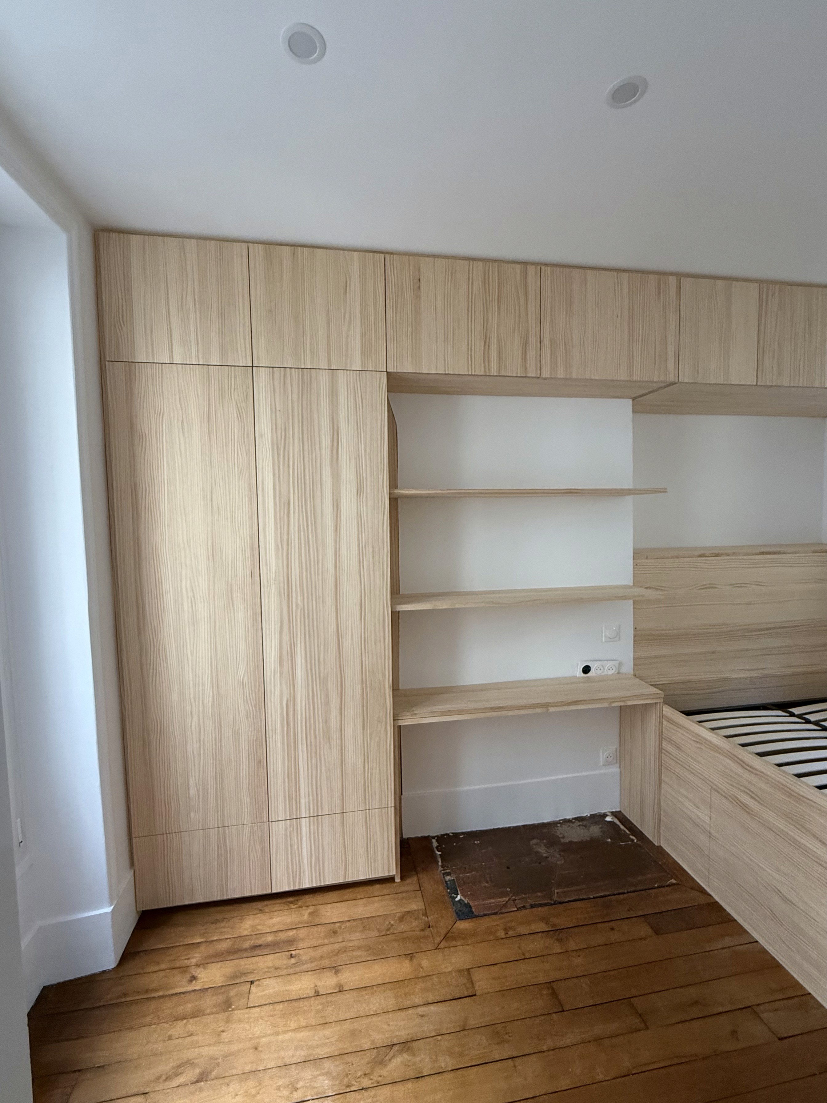 Menuiserie sur-mesure en bois clair avec étagères et placards de rangement intégrés pour un gain de place maximal.