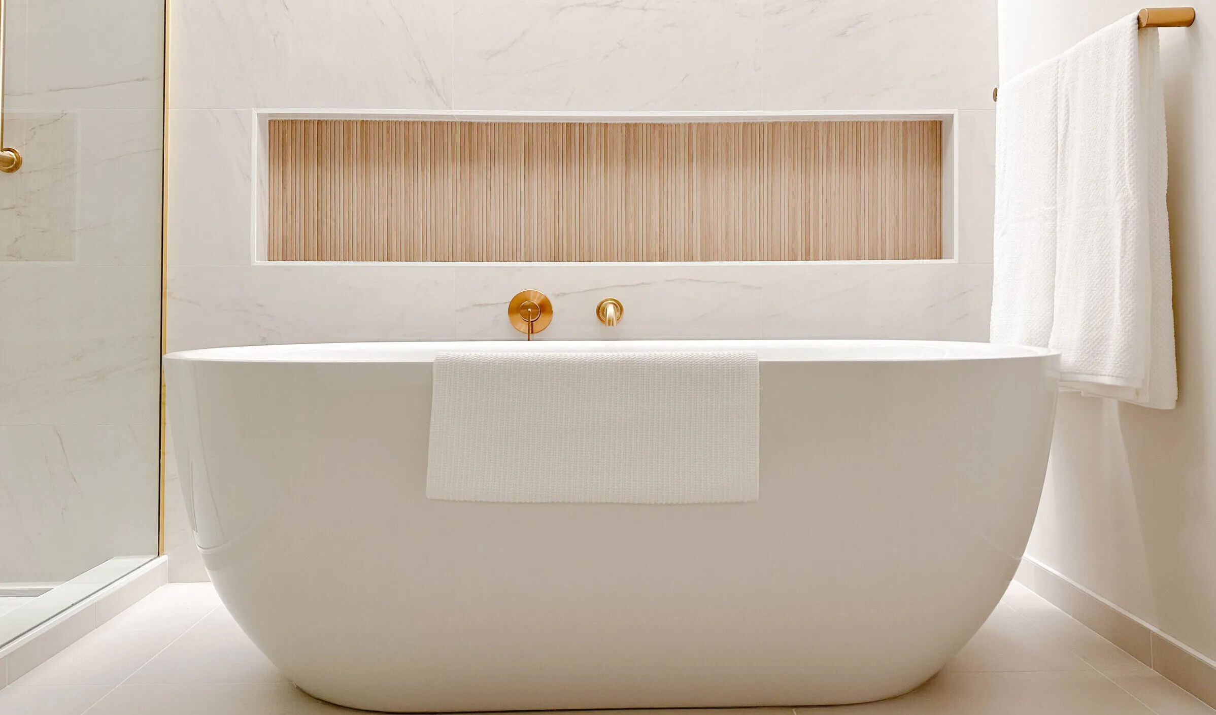 Image of freestanding bathtub with tile niche behind.