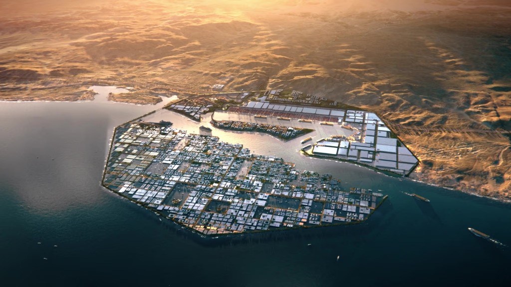 منظر جوي واسع لمدينة أوكساجون نيوم يبرز التصميم المثمن الفريد العائم فوق البحر الأحمر، مع تباين ساحر بين زرقة المياه والرمال الذهبية للصحراء الشاسعة في الخلفية.