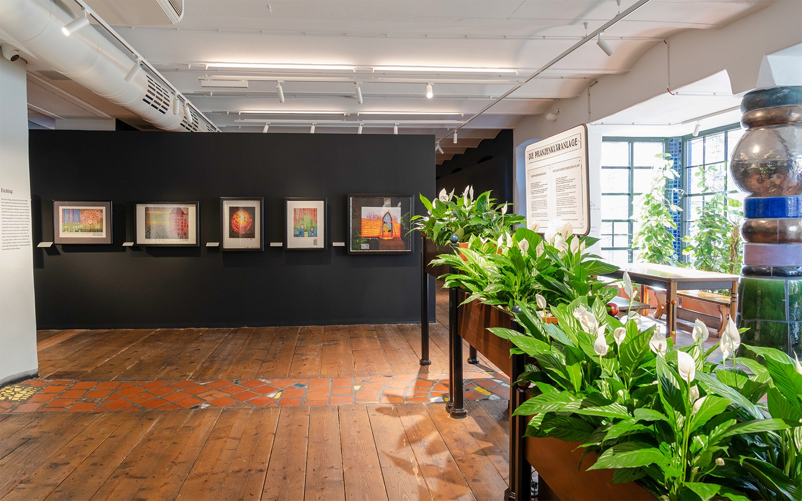Pameran KUNST HAUS WIEN dengan karya seni berbingkai dan tanaman hijau yang subur di Museum Hundertwasser.