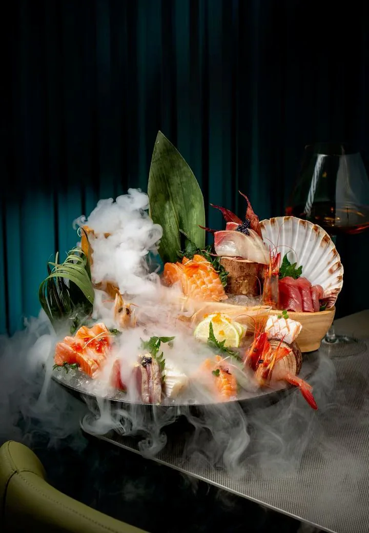 Plateau de sashimis, crevettes et coquille Saint-Jacques dans un nuage de fumée