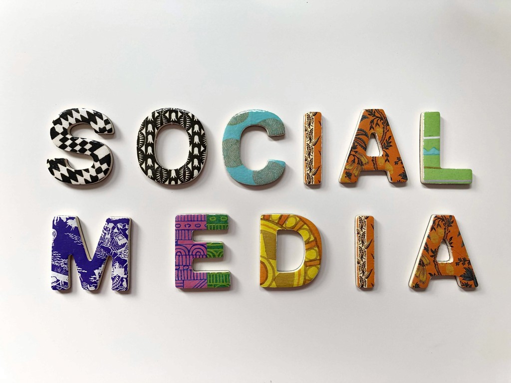 The phrase "Social Media" is spelled out in colorful, patterned letters, each uniquely designed, highlighting the vibrant and diverse nature of online interactions and platforms.