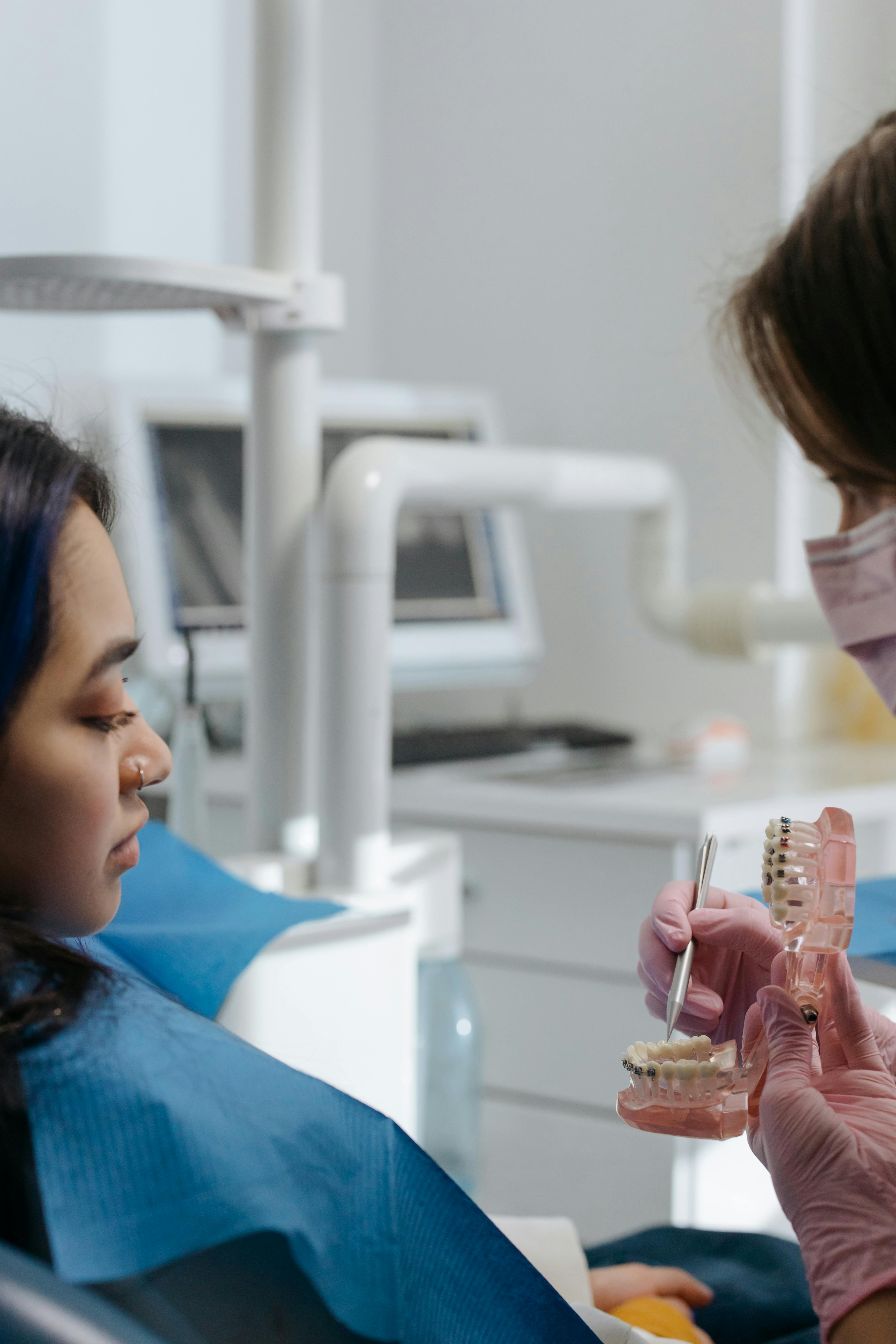 A picture of dentist showing dental model to patient during orthodontic consultation