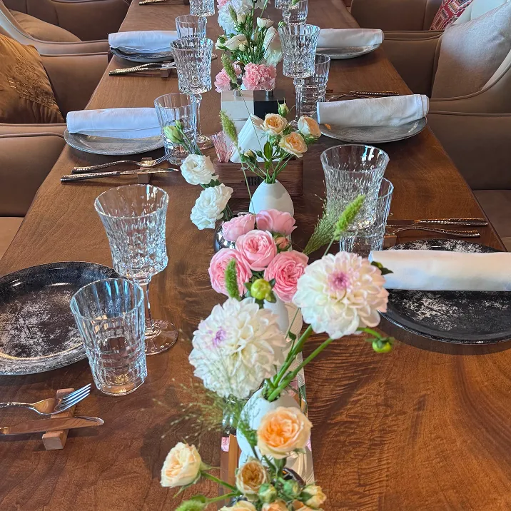 Elegant dining table with floral centerpiece, black plates, and white napkins