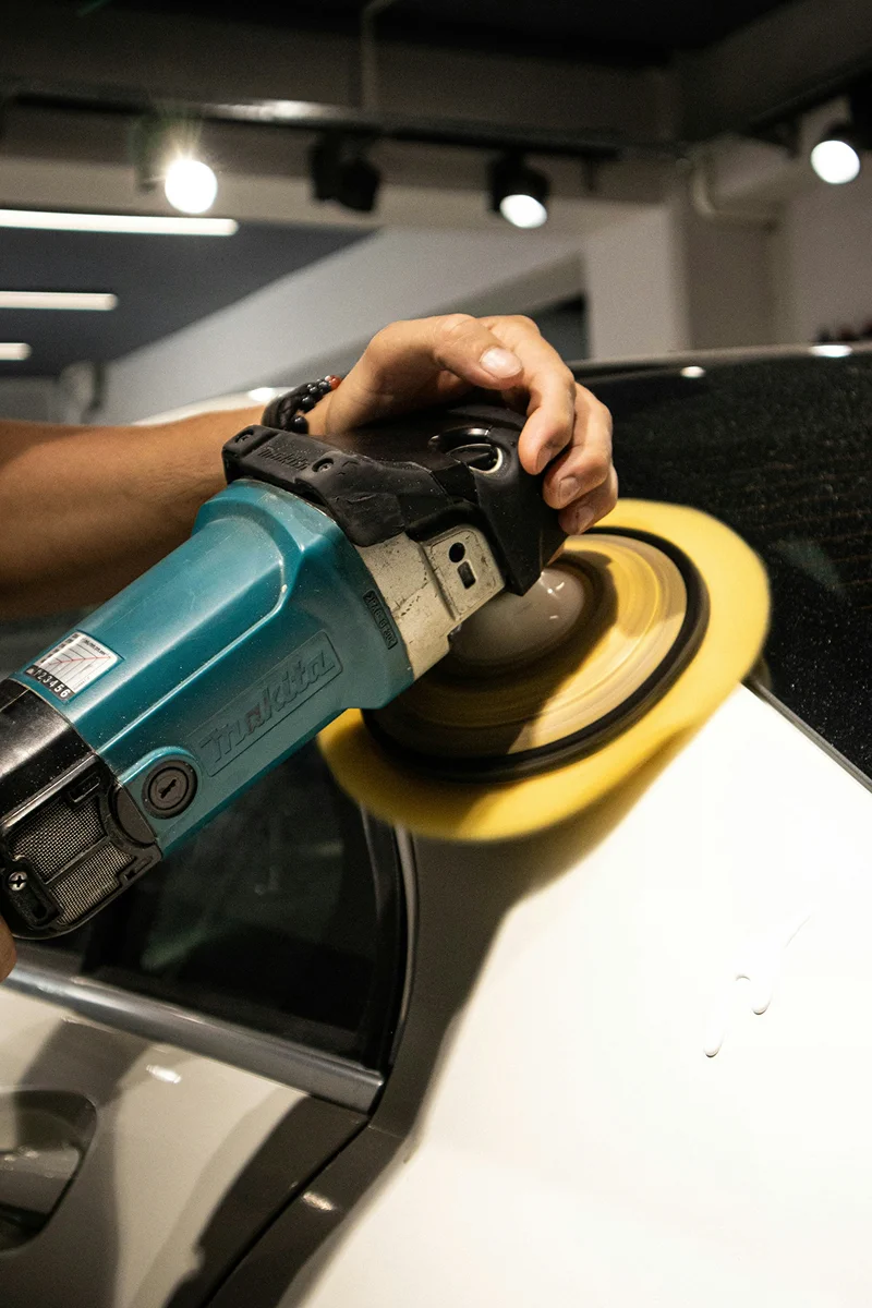 Professional paint correction process using a polishing machine to restore vehicle paint surface.