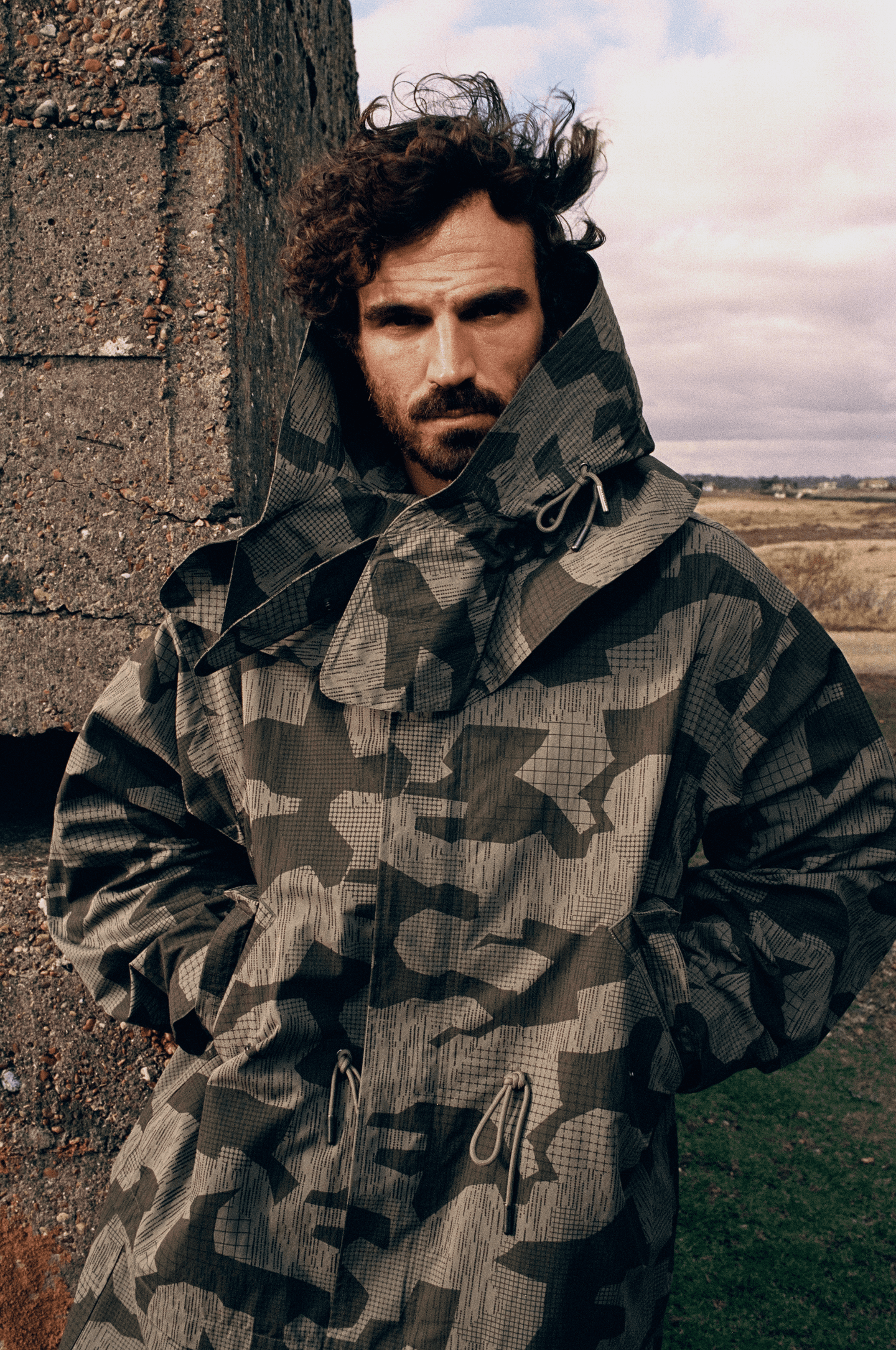 Un mannequin qui porte une parka camouflage de la marque Belstaff proche de la mer