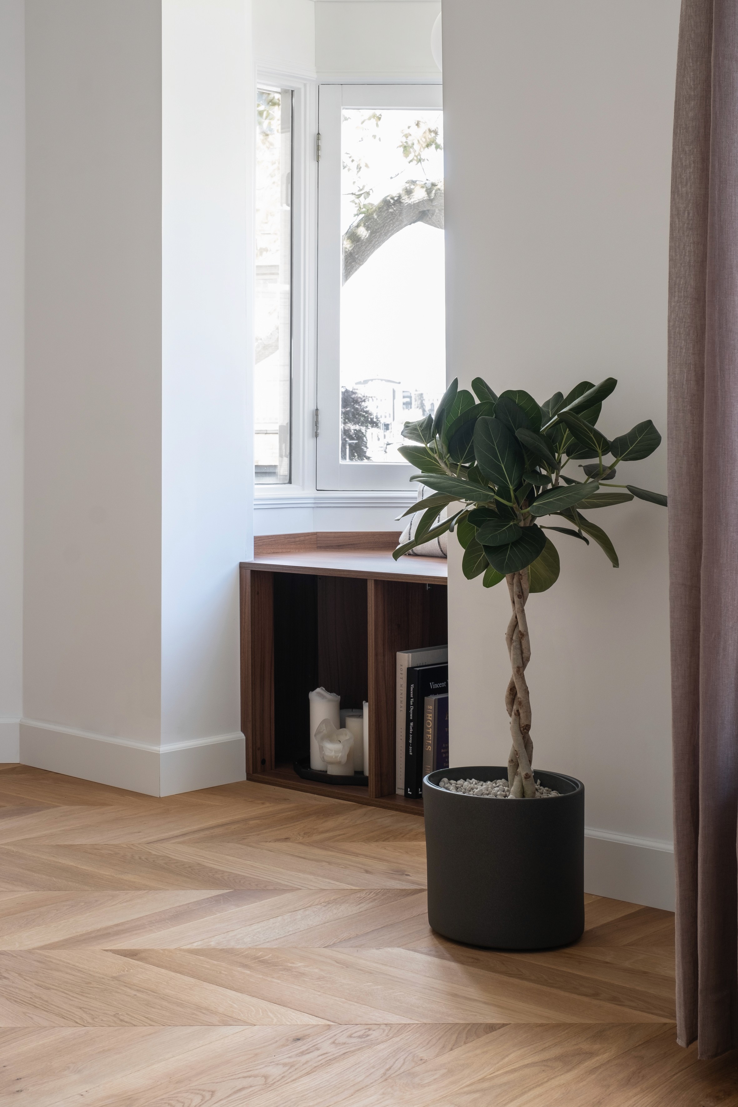 Living area corner with walnut bookshelf, fiddle leaf fig plant in black ceramic pot, and Hungarian Point floor