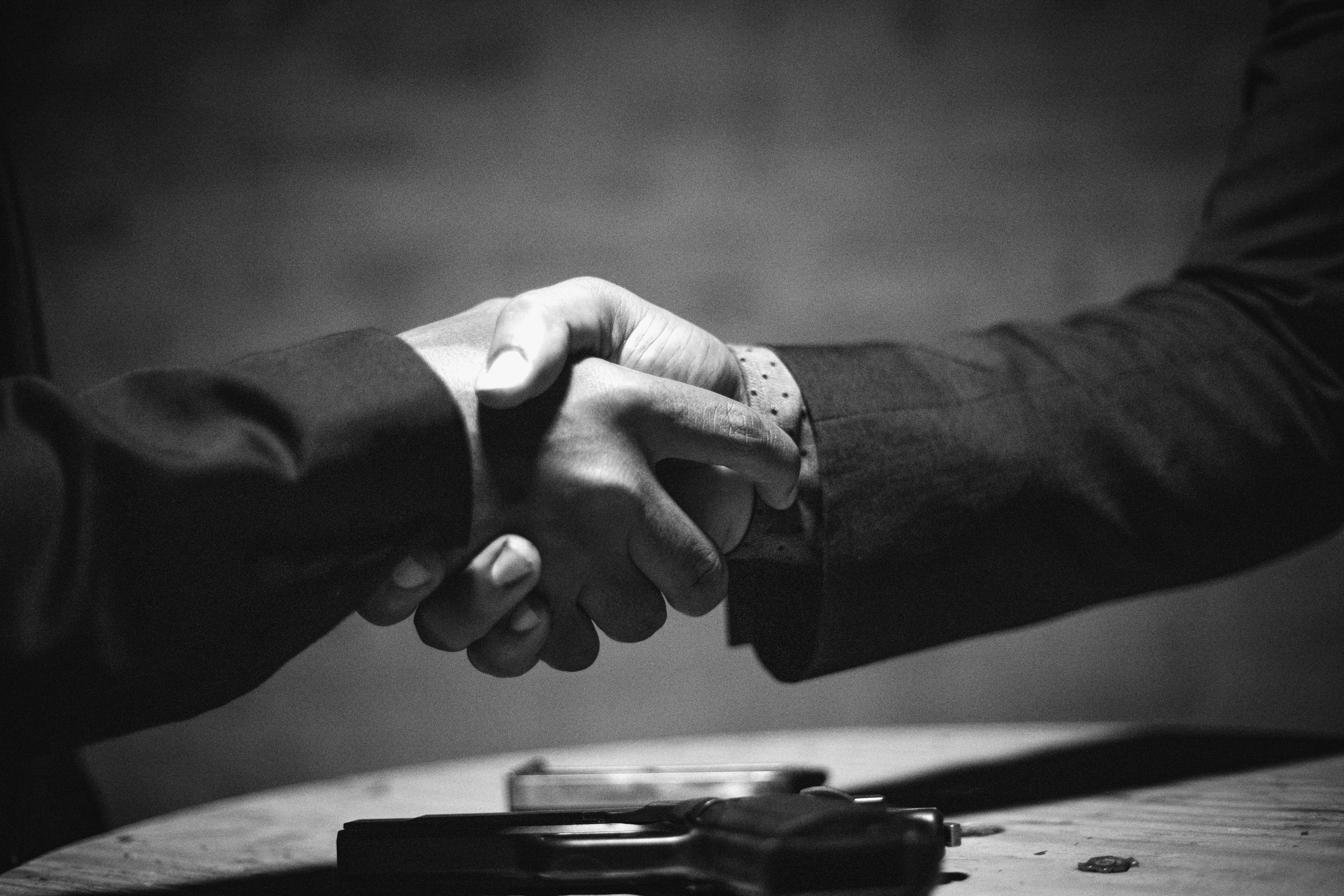 two people shaking hands over a wooden table