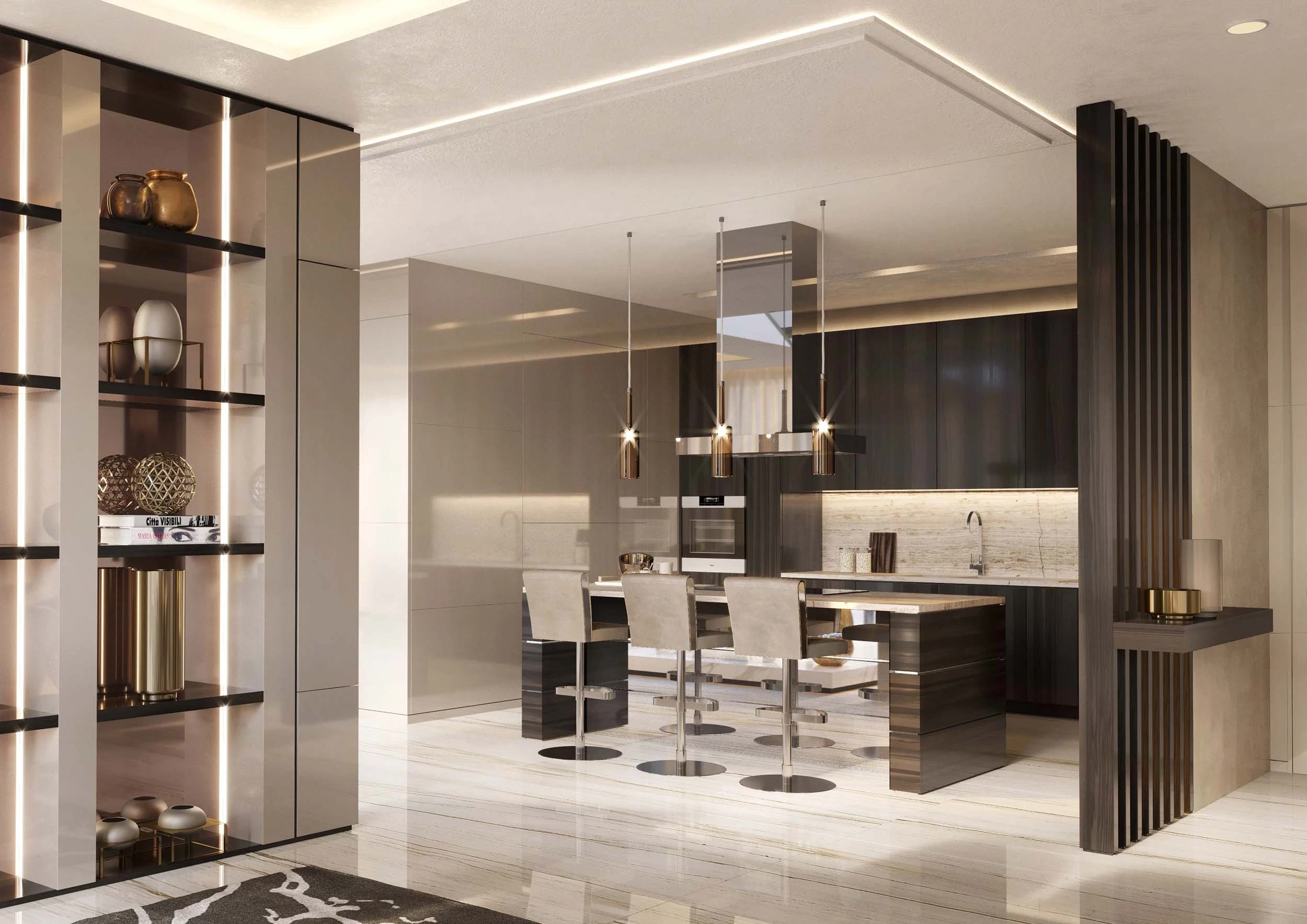 Modern kitchen area with sleek design. Features an island with three beige upholstered bar stools, hanging pendant lights, built-in appliances, and dark cabinetry. To the left, there are shelves with stylish decor items and gold accents.