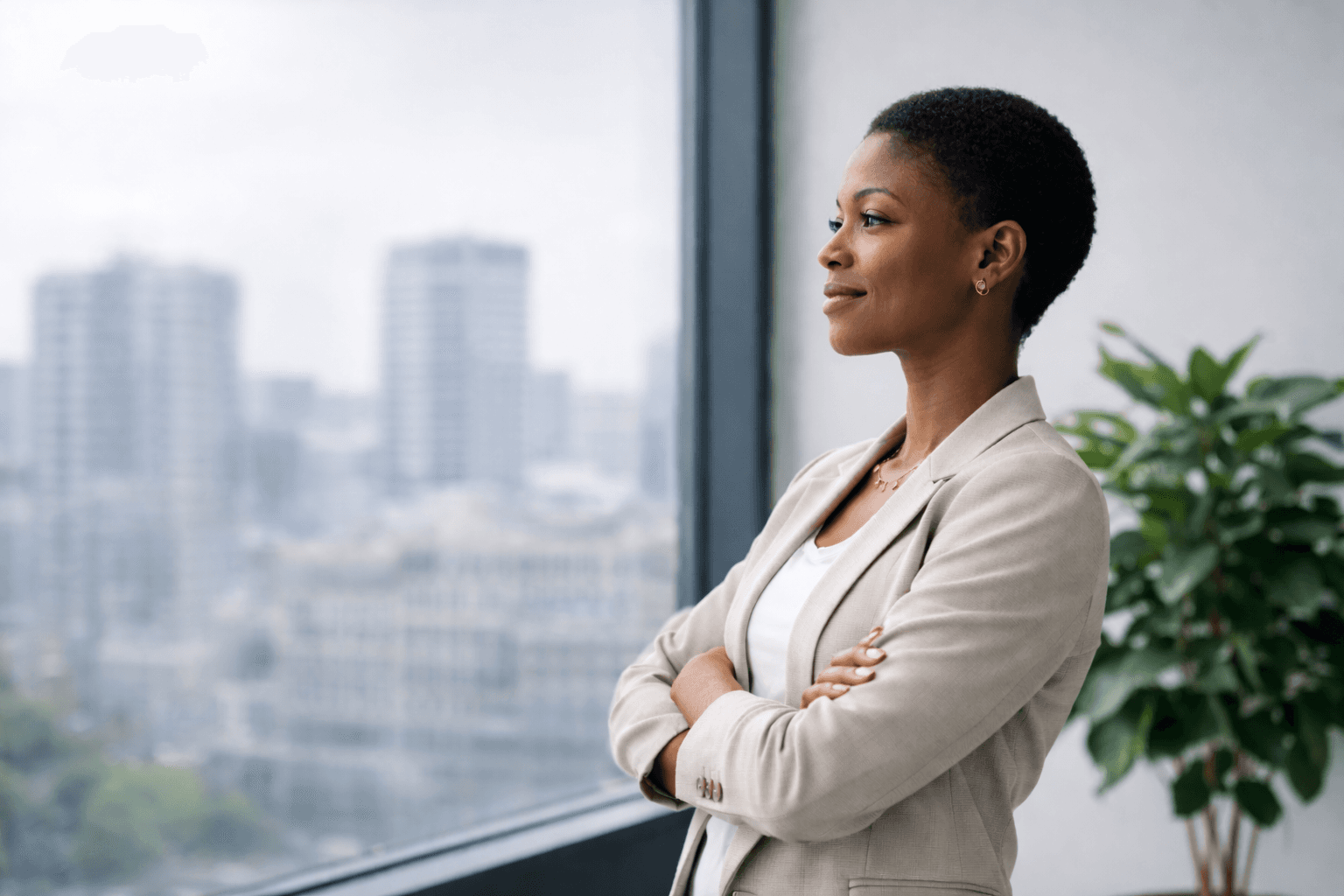 Frau steht selbstbewusst am Fenster eines modernen Büros mit Blick auf die Stadt.