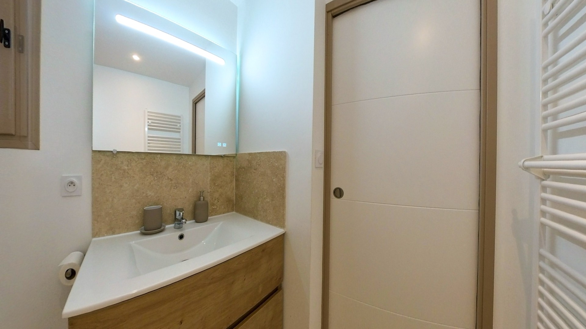 Meuble vasque suspendu en bois avec miroir rétroéclairé LED et crédence en pierre naturelle.