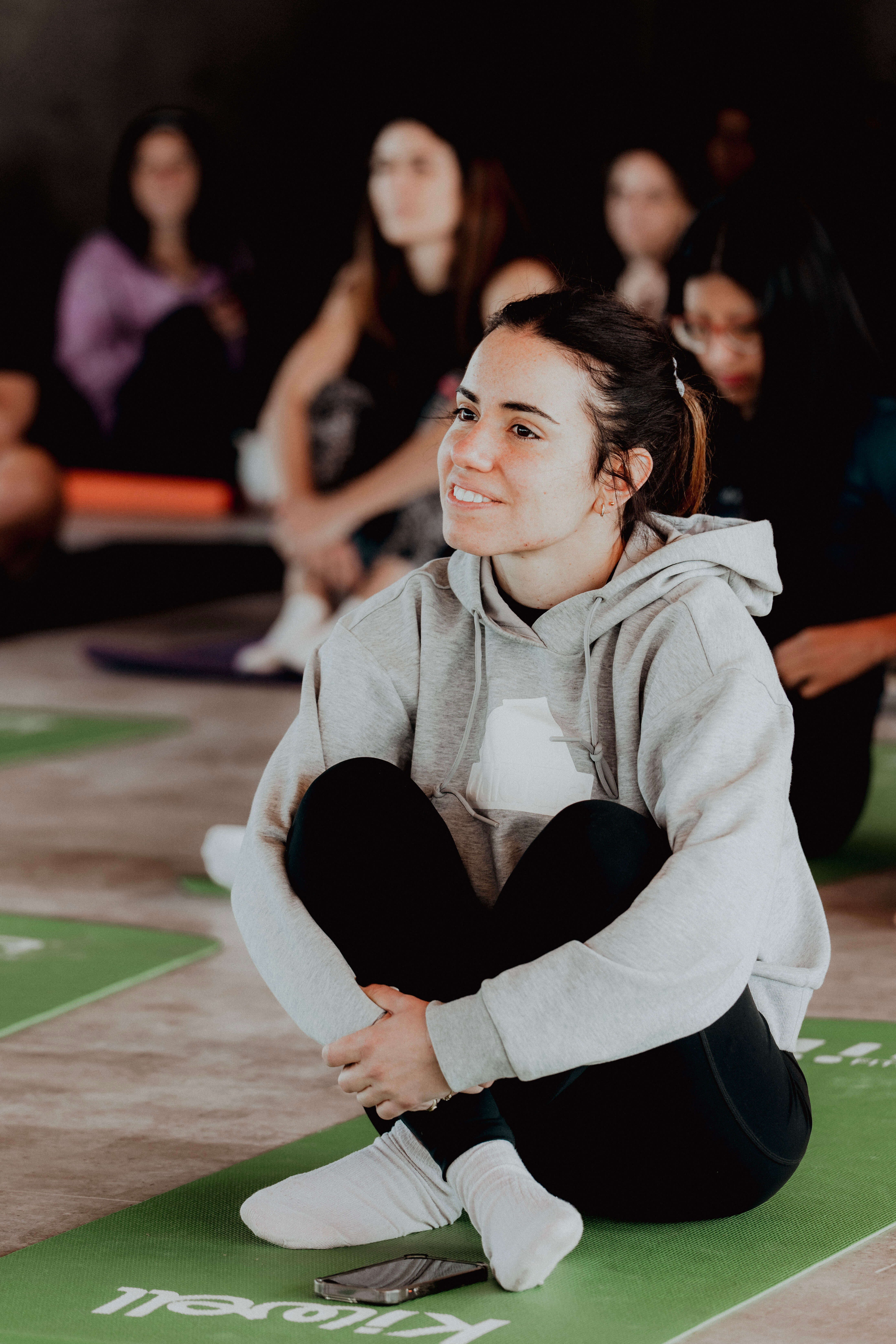 Persona sentada en una esterilla durante una actividad tranquila en grupo, transmitiendo una sensación de pausa y bienestar.