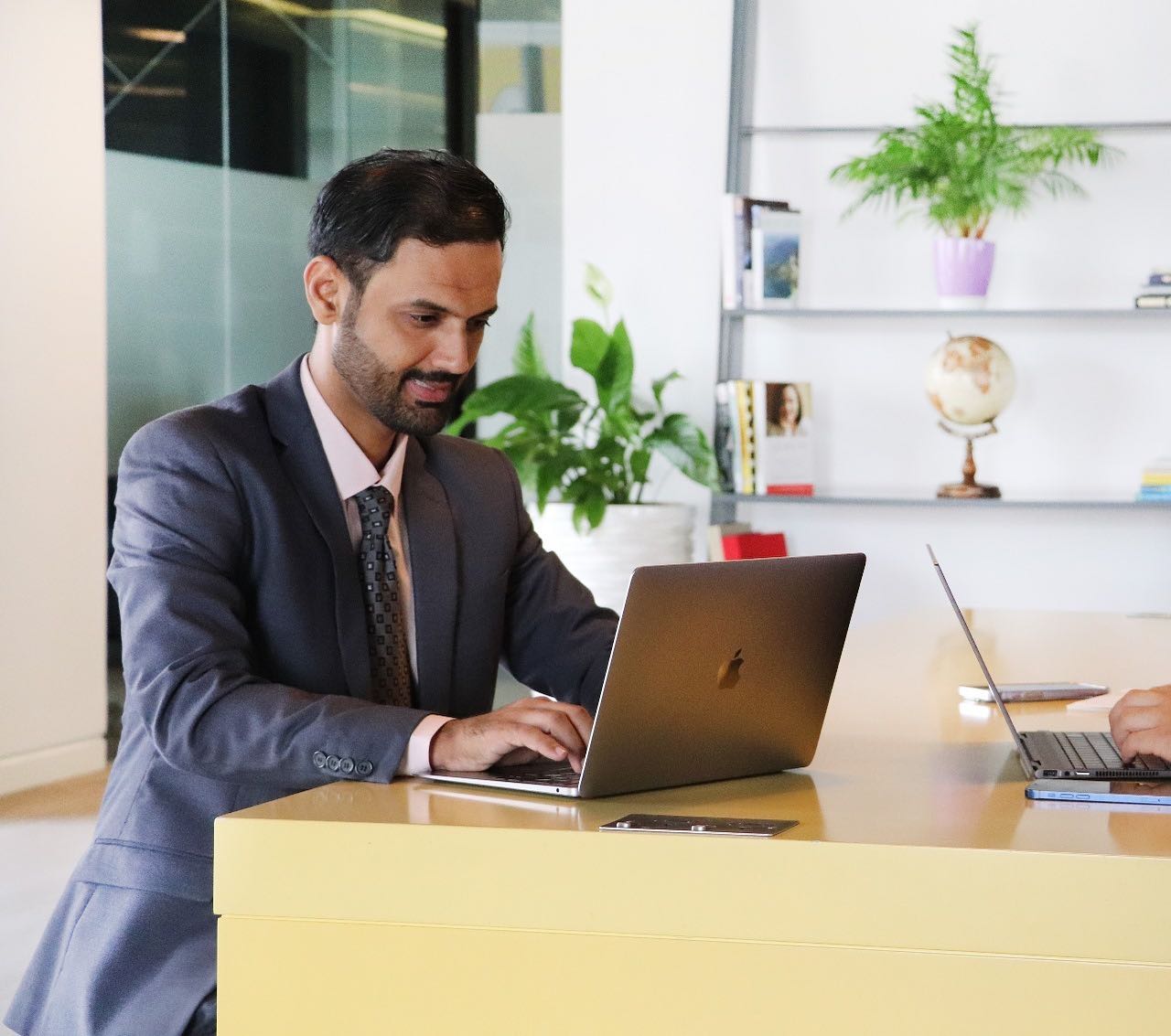 A professional man working on a laptop in a modern office, illustrating the key components of a virtual office setup by myOffice.