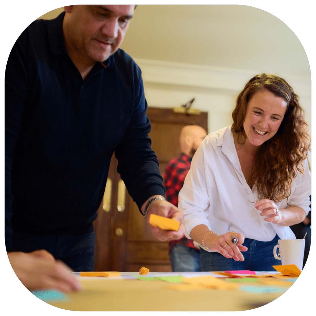 two people stand over a desk with post it notes on