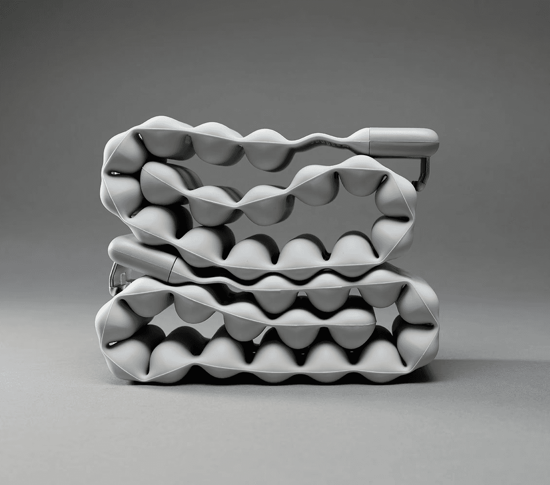 Flexible segmented wearable weight prototype shown coiled on a gray background