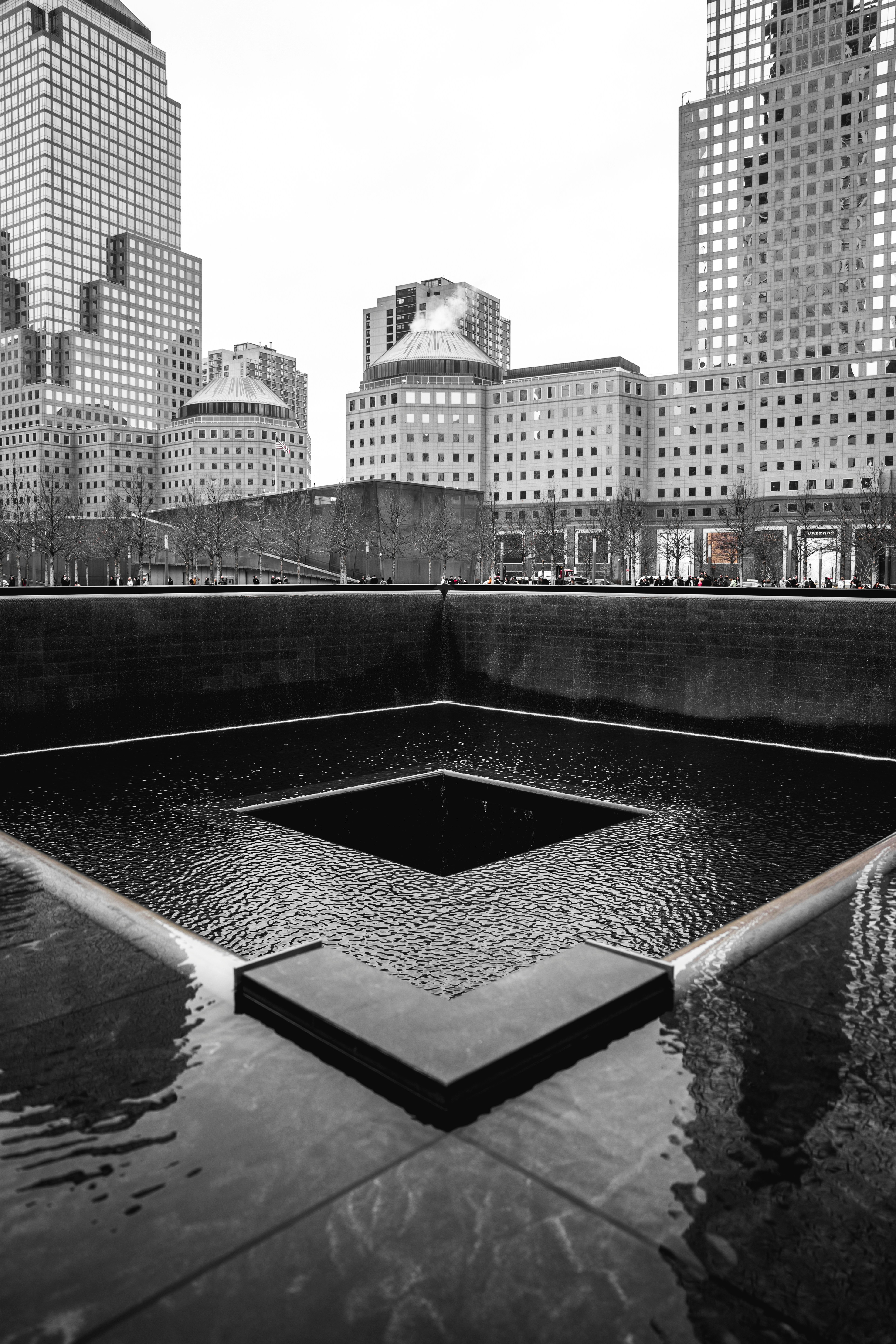 Black and white photo of one of the large pools of water at the footprint of where the World Trade Center tower once stood..