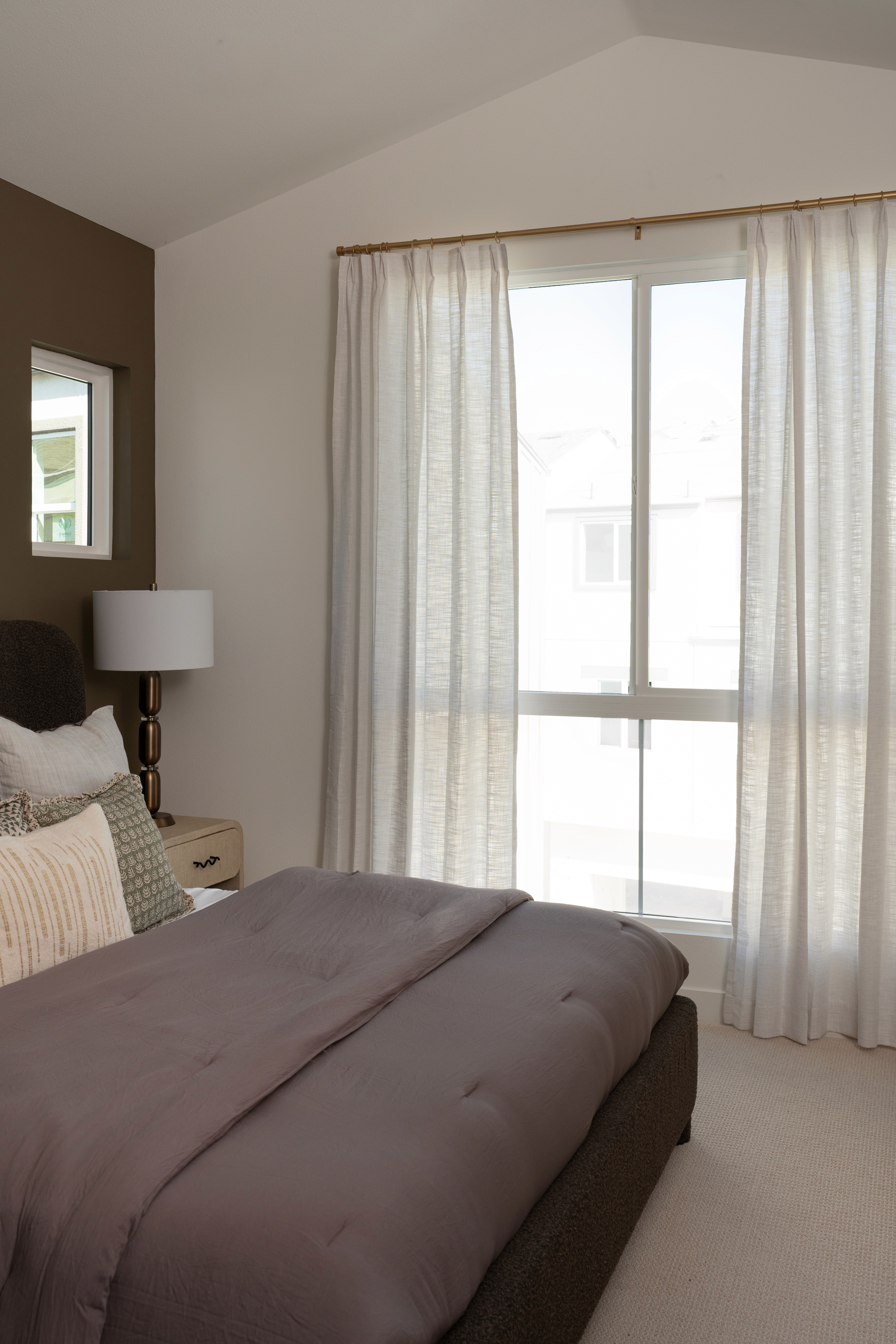 View of bed, side table and window in primary bedroom