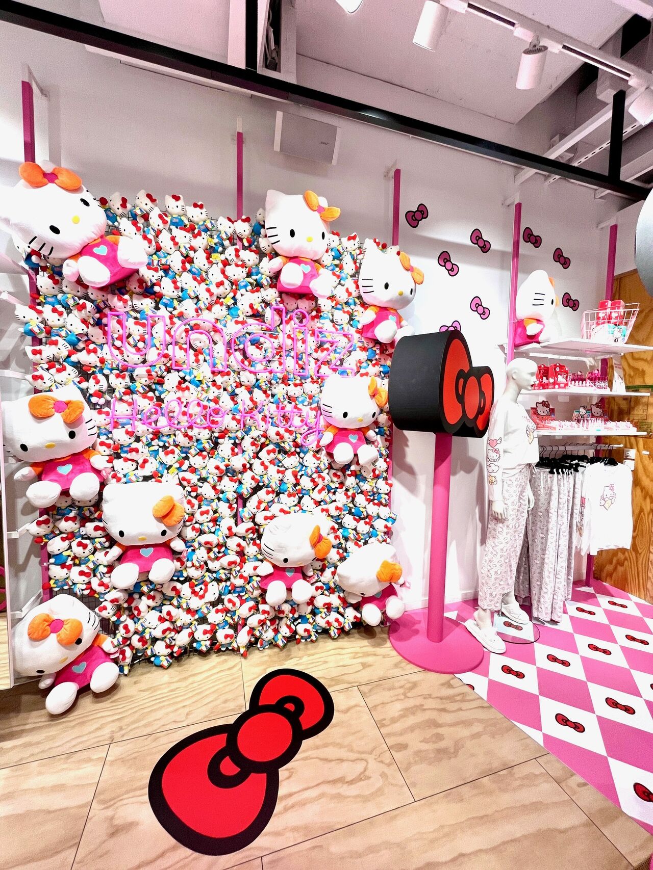 Boutique Undiz décorée avec des peluches Hello Kitty, un sol à damier rose et des vêtements de la collection.