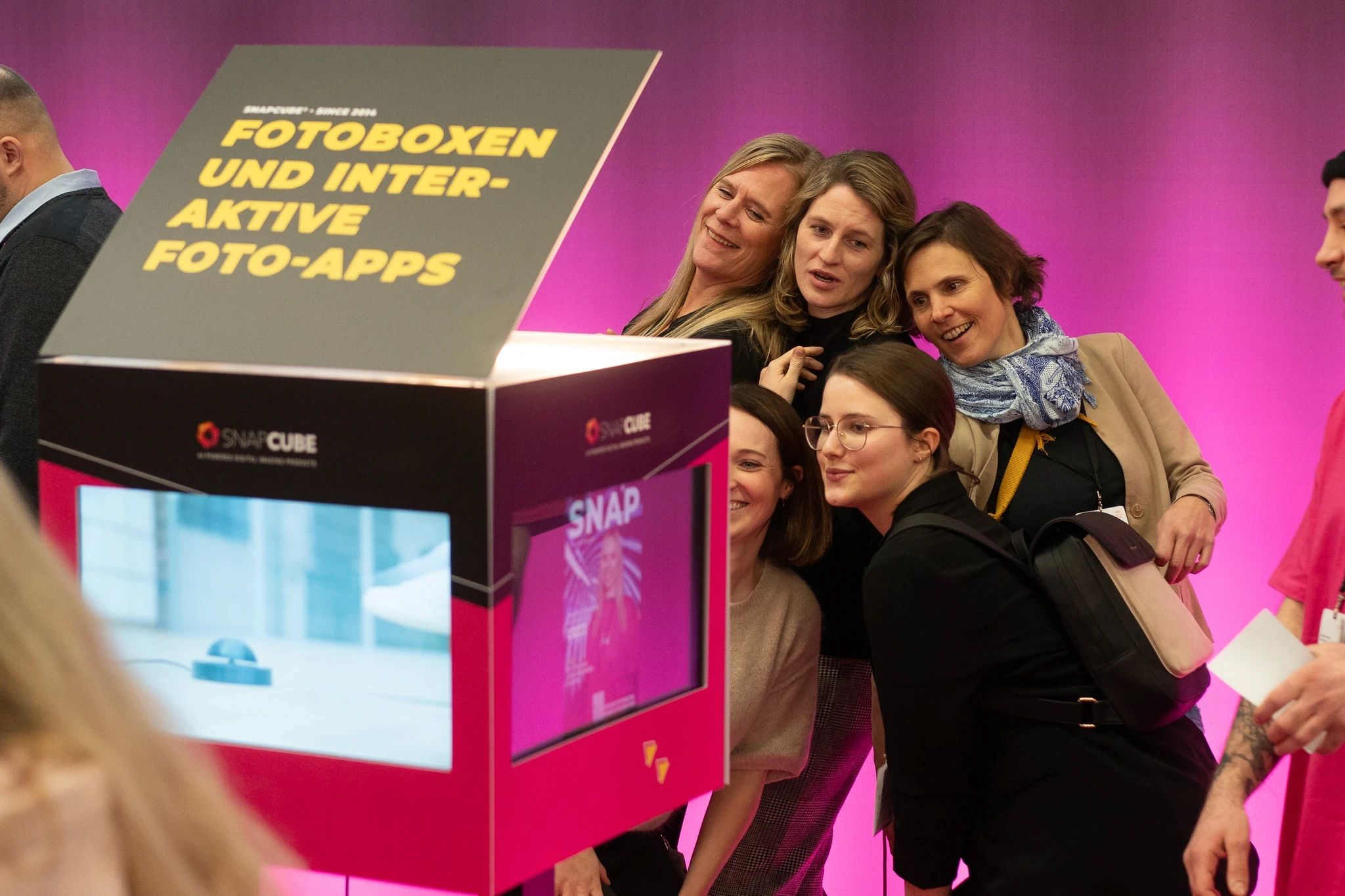 Besucherinnen der BOE Messe in Dortmund machen Fotos an der SnapCube® Fotobox CUBE