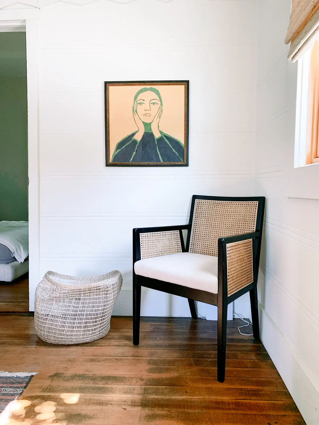 Cane-back chair, artwork, and woven basket in room.