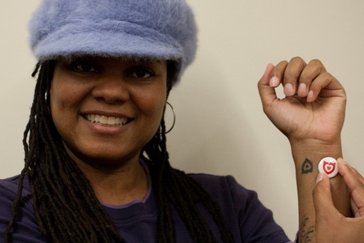 A woman with a tattoo of the Loving Day logo on her har near her wrist.