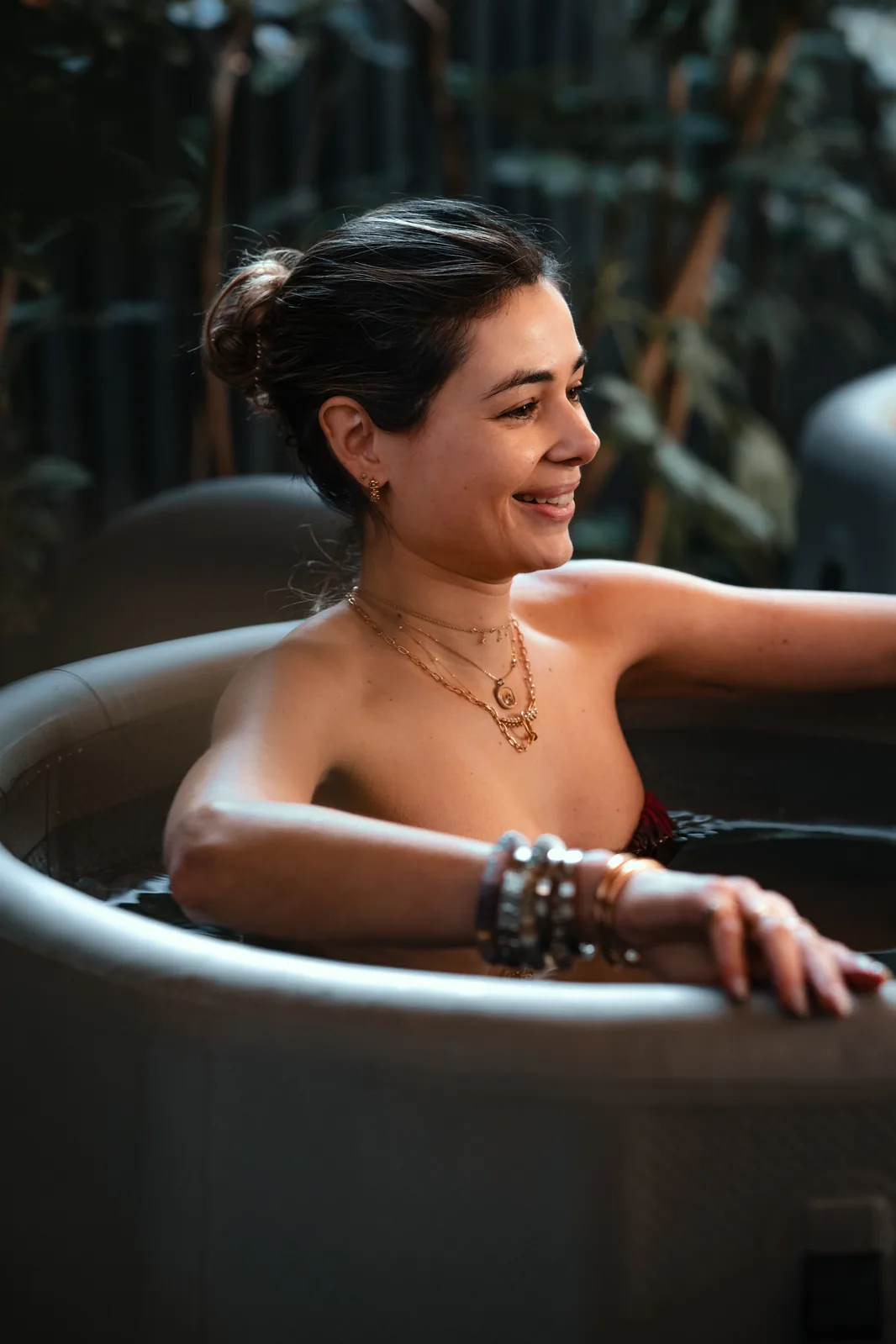 A woman smiling while sitting in an ice bath