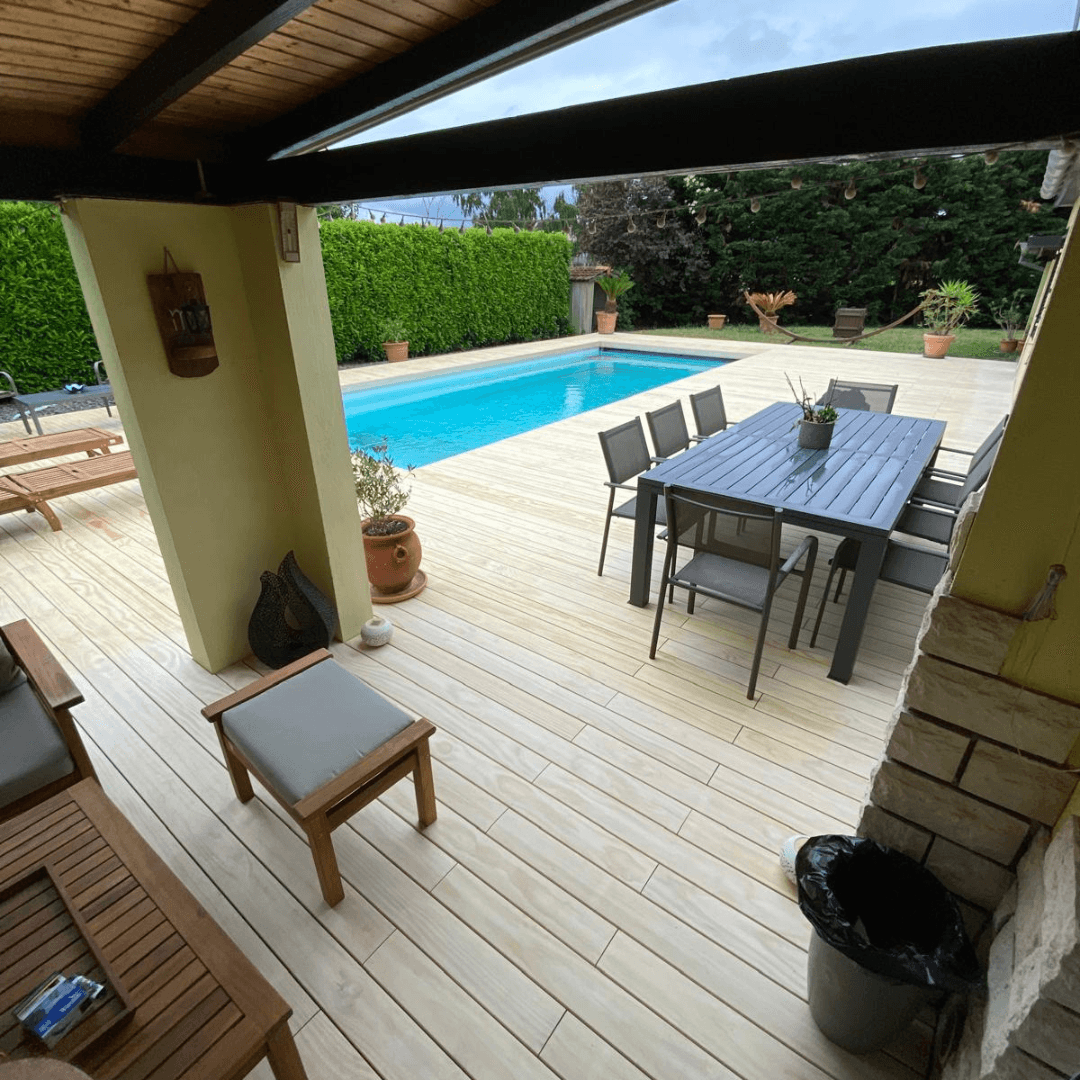 Four individuals stand closely together, smiling, wearing white outfits and one in blue, against a plain backdrop.