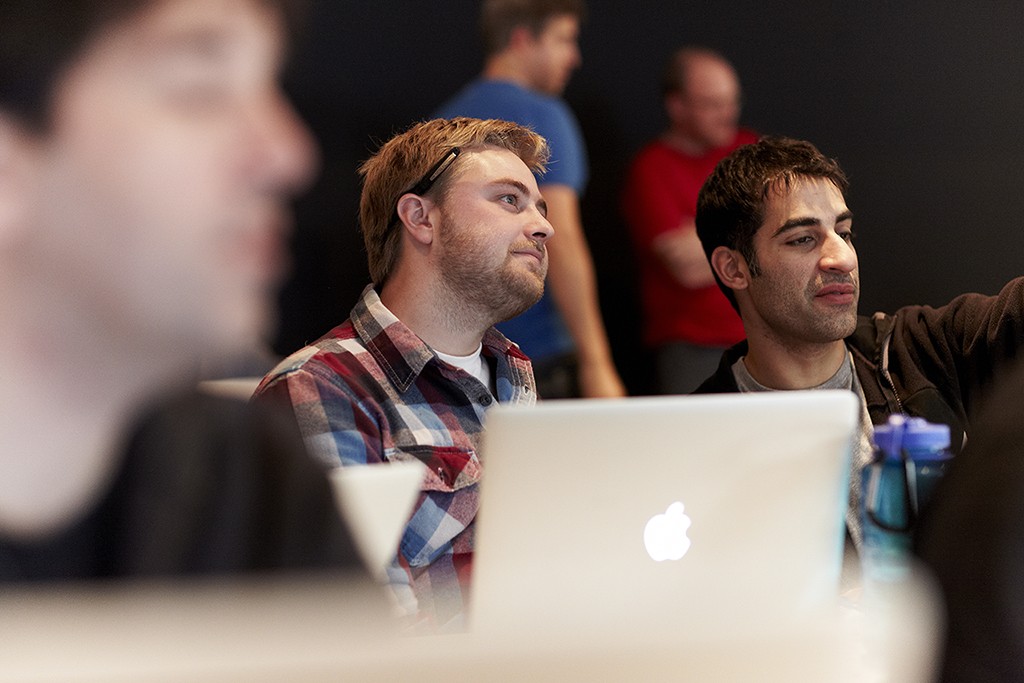 Two designers seated at laptops in a studio, engaged and absorbing a shared presentation.