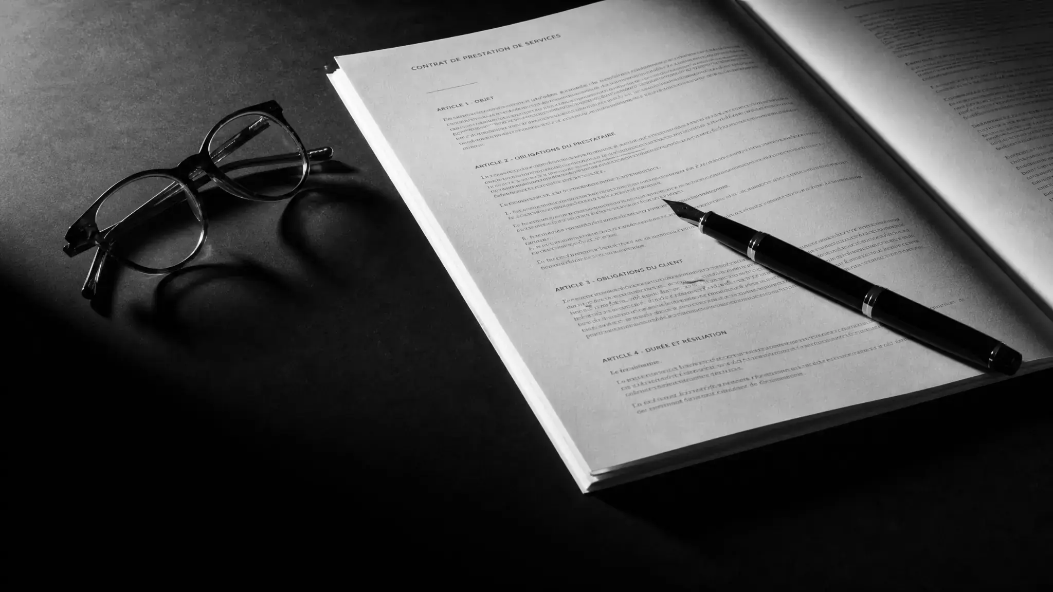 Contrat de prestation de services annoté, lunettes et stylo plume, illustrant la rédaction et la négociation contractuelle.