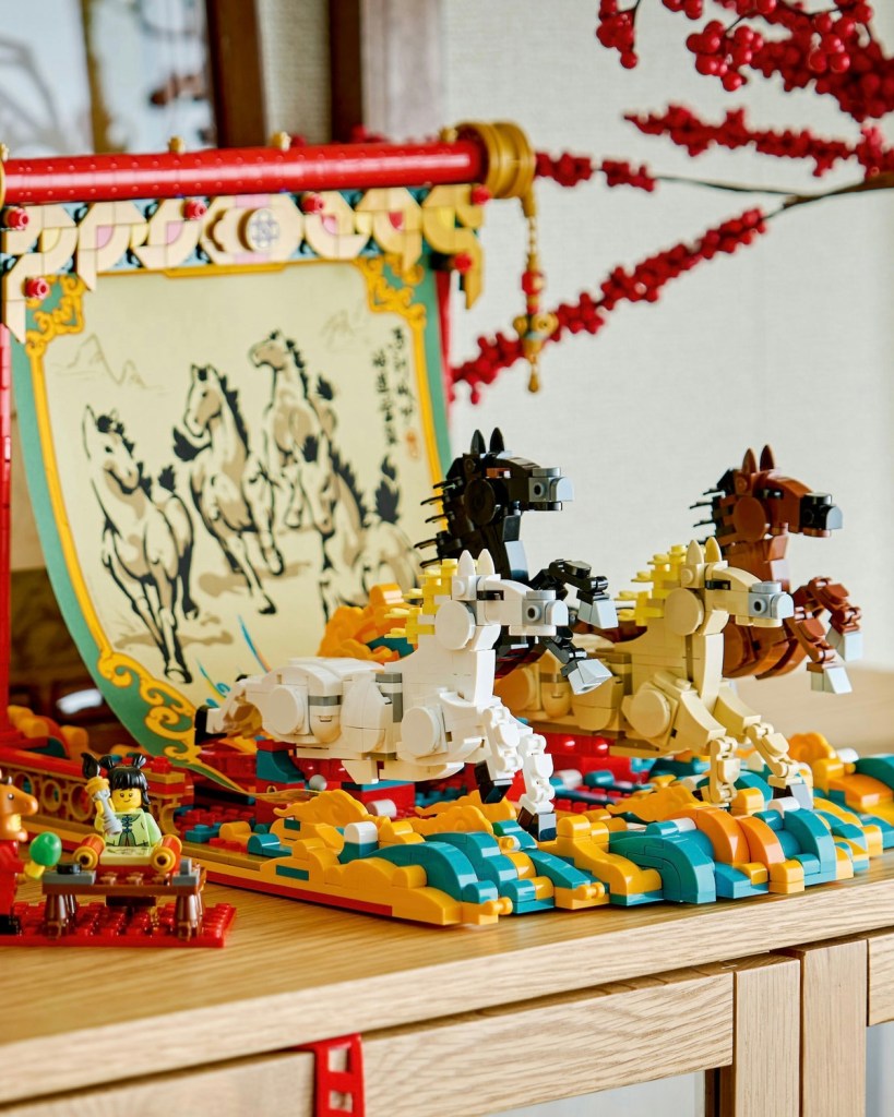 A colorful display of LEGO-style horses in various colors, positioned on a vibrant base, with a decorative backdrop featuring a traditional painting of horses.