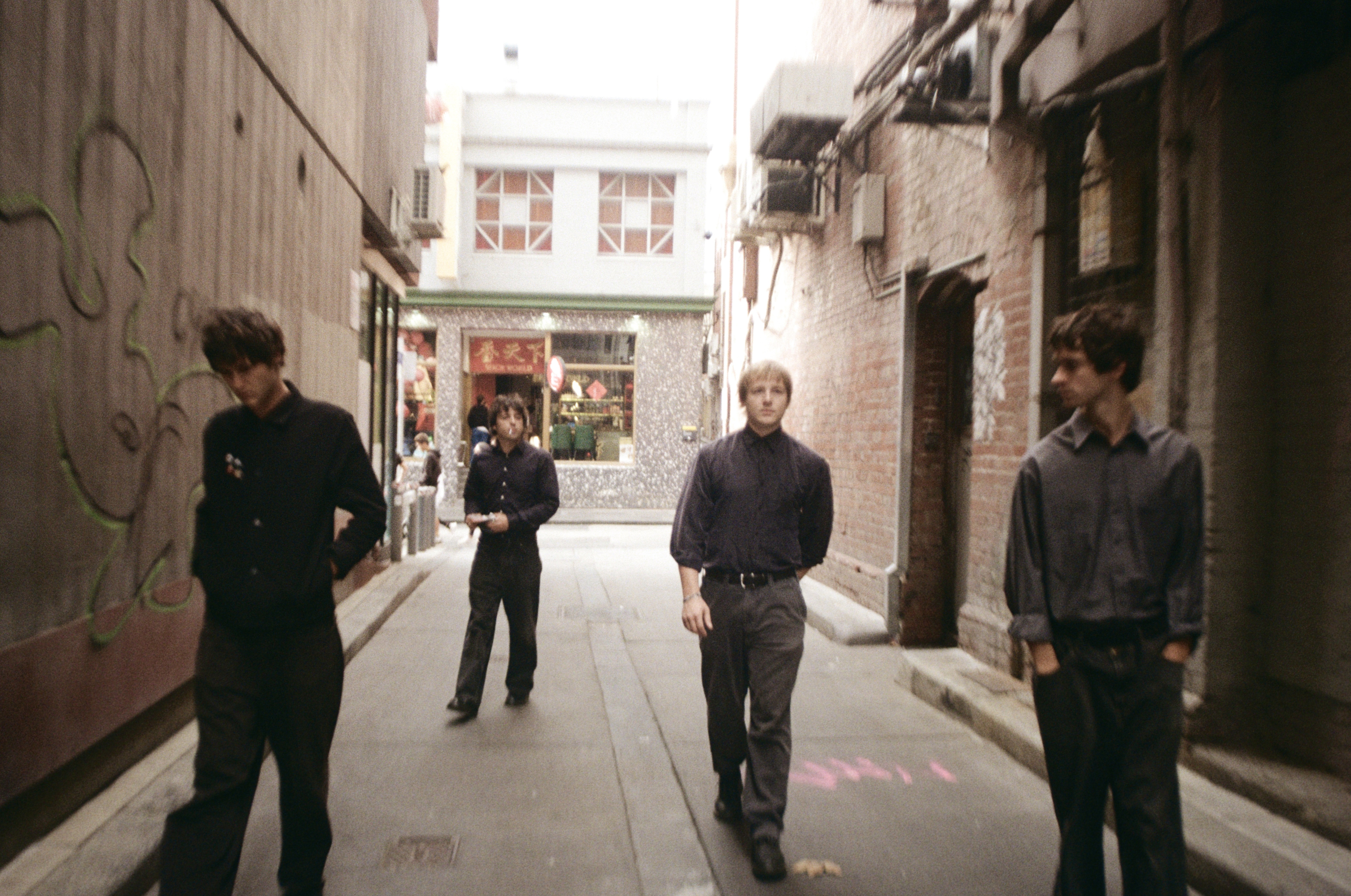The 4 band members walking down an alleyway