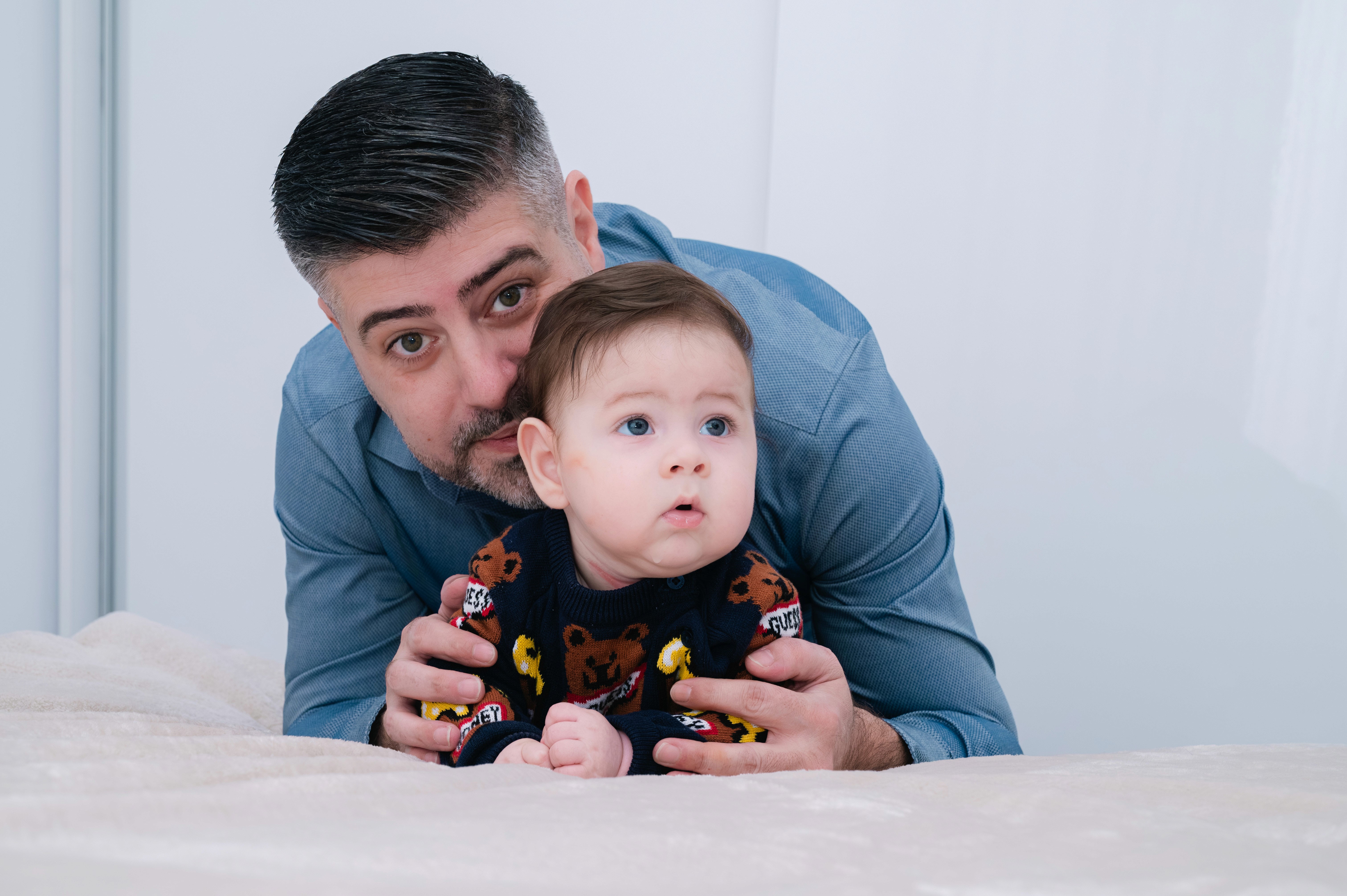 Tatăl ținând copilul în brațe, cadru apropiat din pregătirile de acasă.