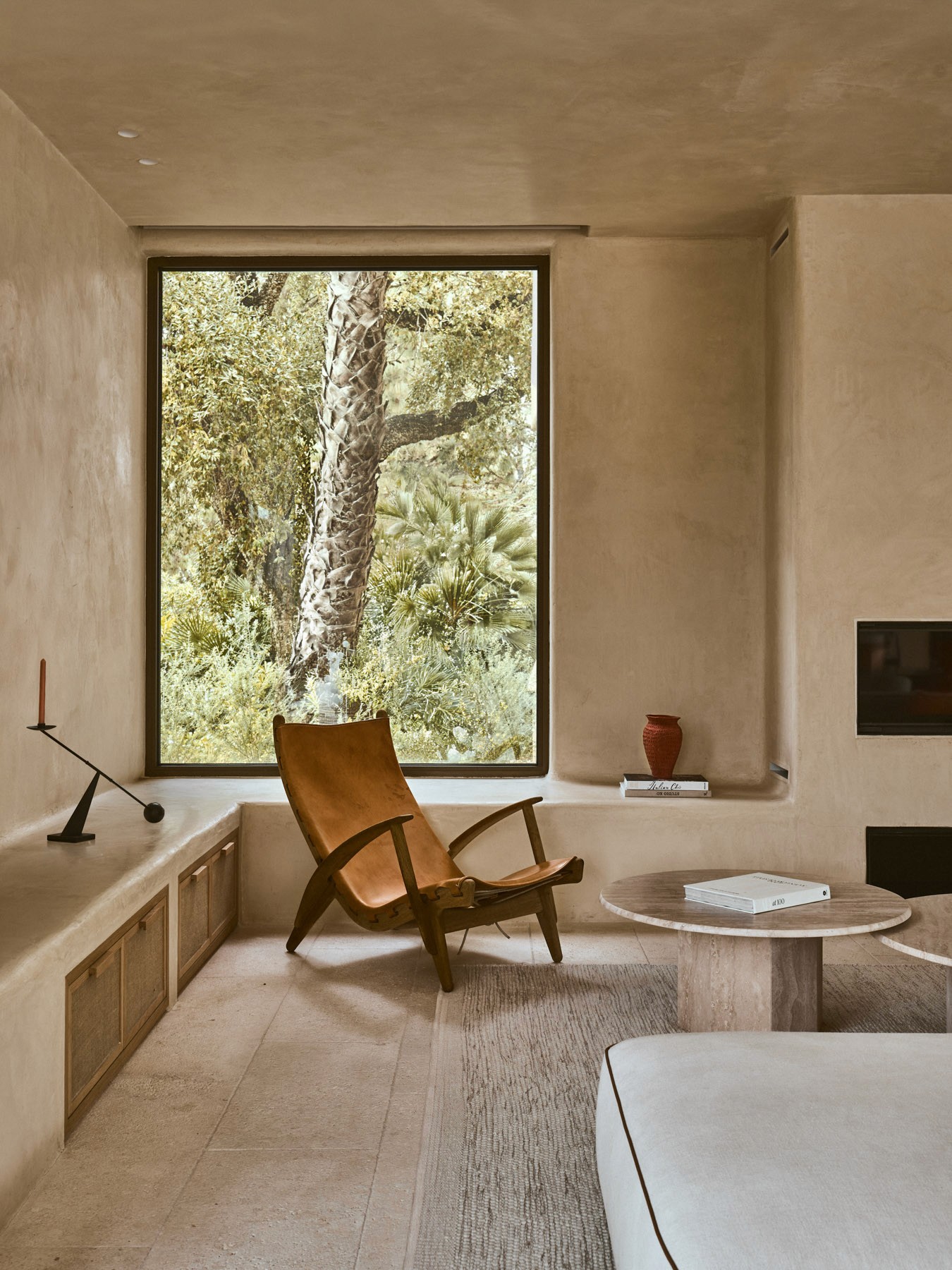 ounge area with natural textures, oak furnishings and floor-to-ceiling window framing the surrounding garden.
