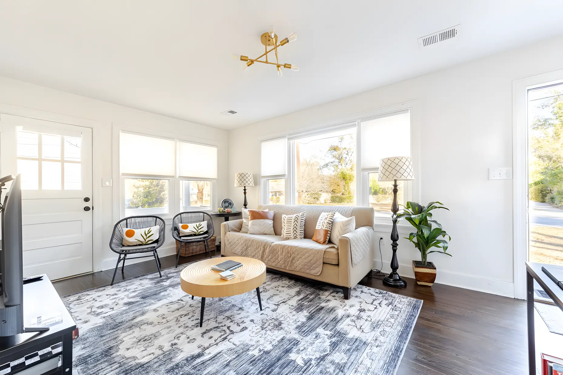 Bright living room with a round wood coffee table, rope chairs and a gold ceiling light