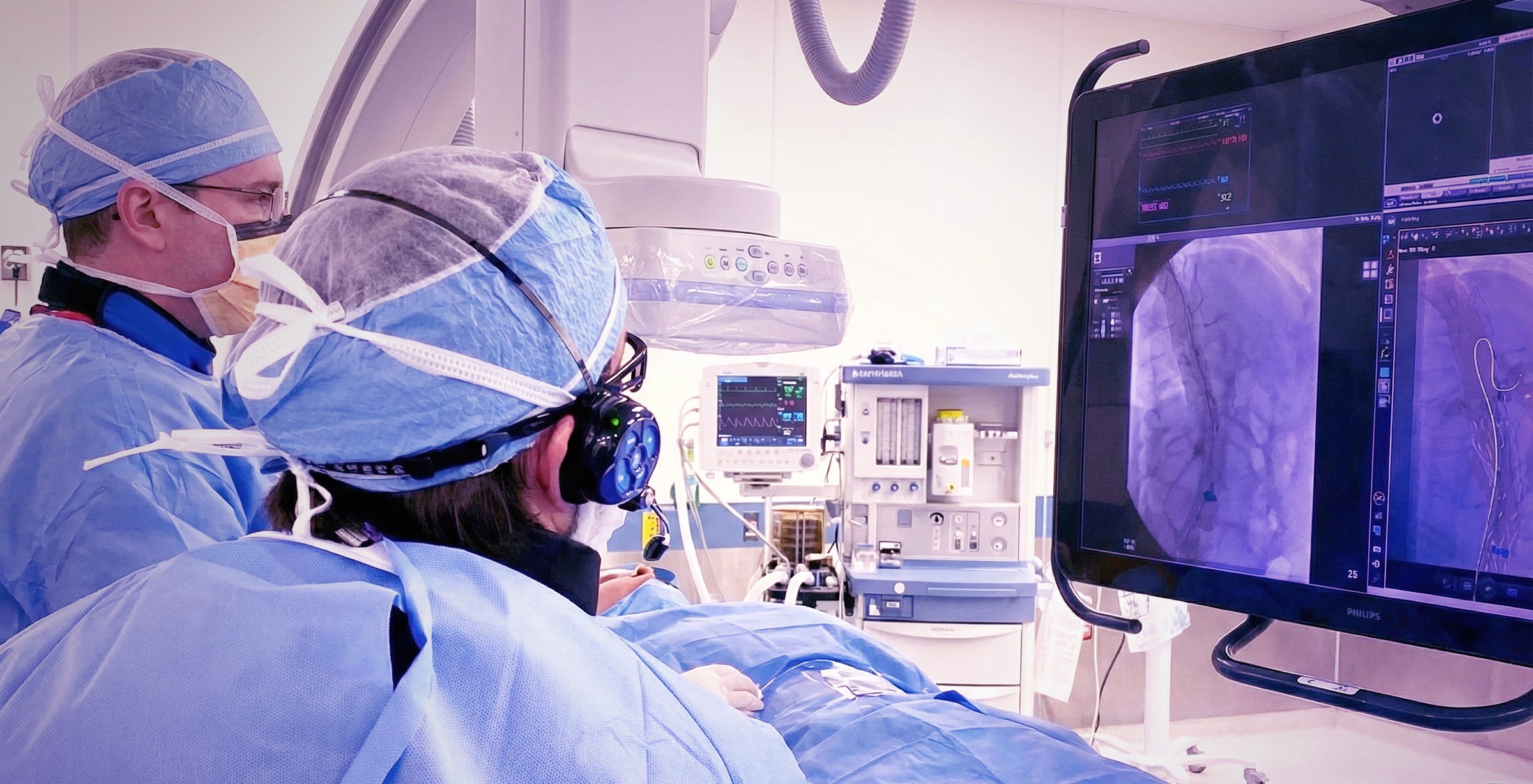 Close-up of a scientist holding a tray of petri dishes with purple cultures, wearing gloves and safety gear.