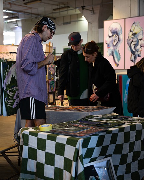 Zdjęcie przedstawiające artystę, któ®y sprzedaje swoje dzieła.