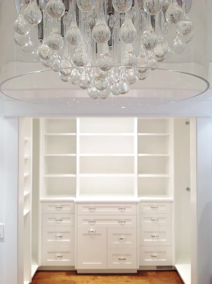 Image of Elegant walk-in closet design with custom shelving, drawers, and chandelier by KHD Homes interior designers.