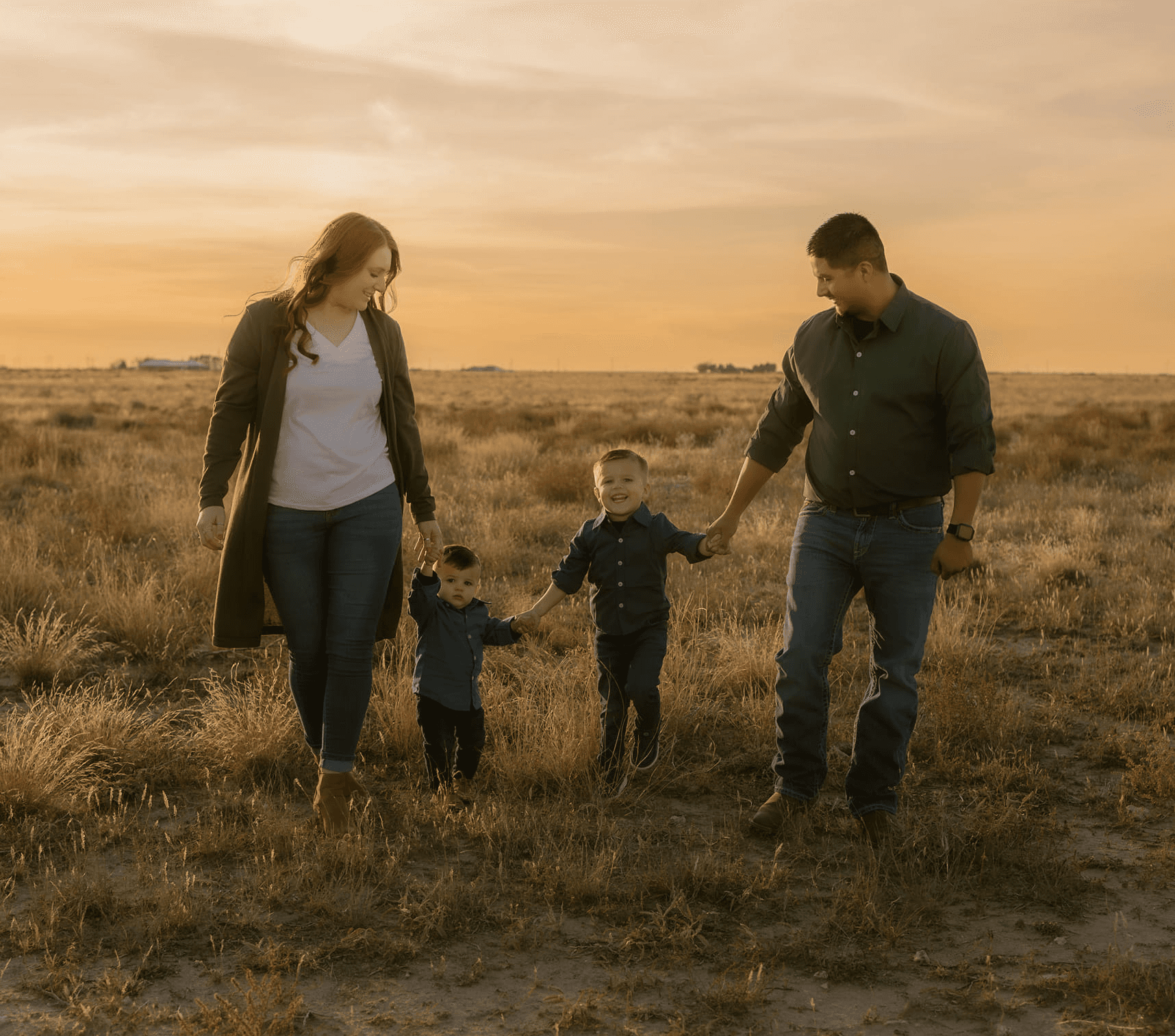 A family sits closely on a rocky landscape with short grasses.