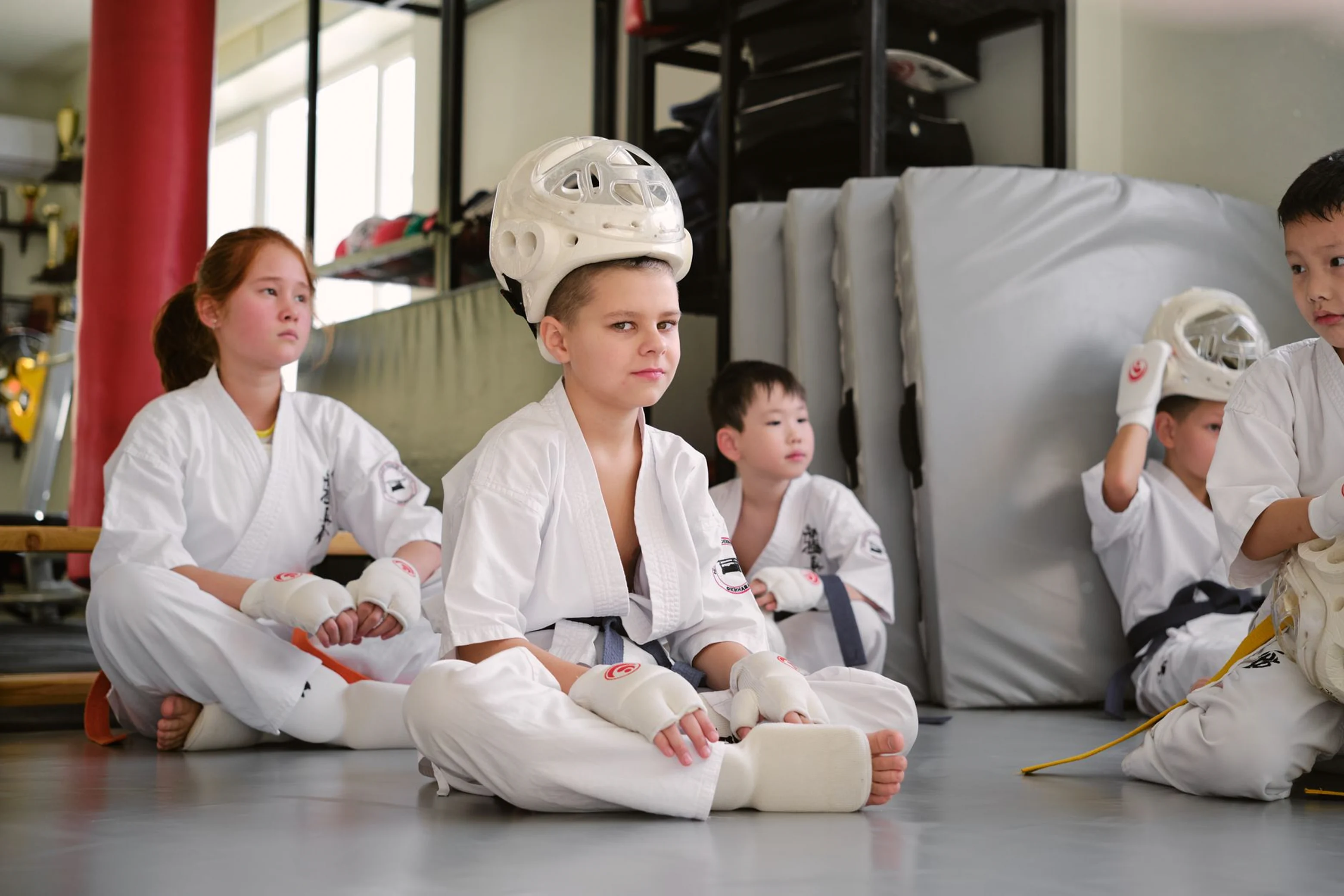 Child sitting on the training mat during a kids martial arts class at Rai Martial Arts.