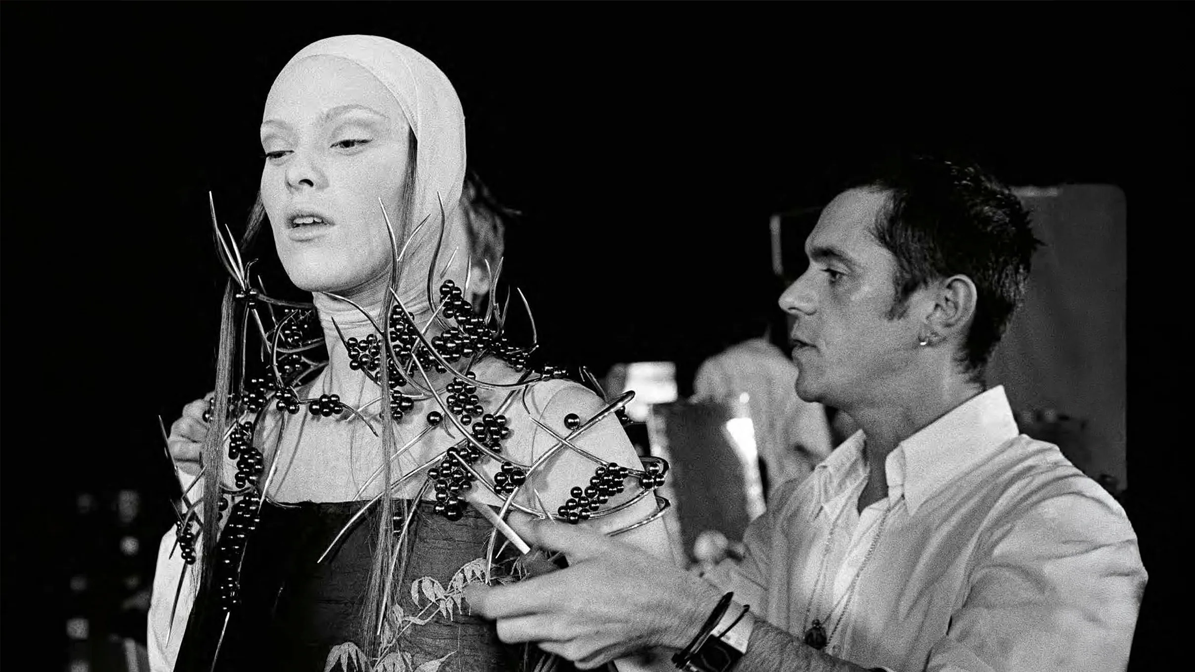 Backstage archival photo of a model wearing an intricate shoulder piece made of silver thorns and freshwater pearls, created by Shaun Leane for Alexander McQueen's VOSS show.