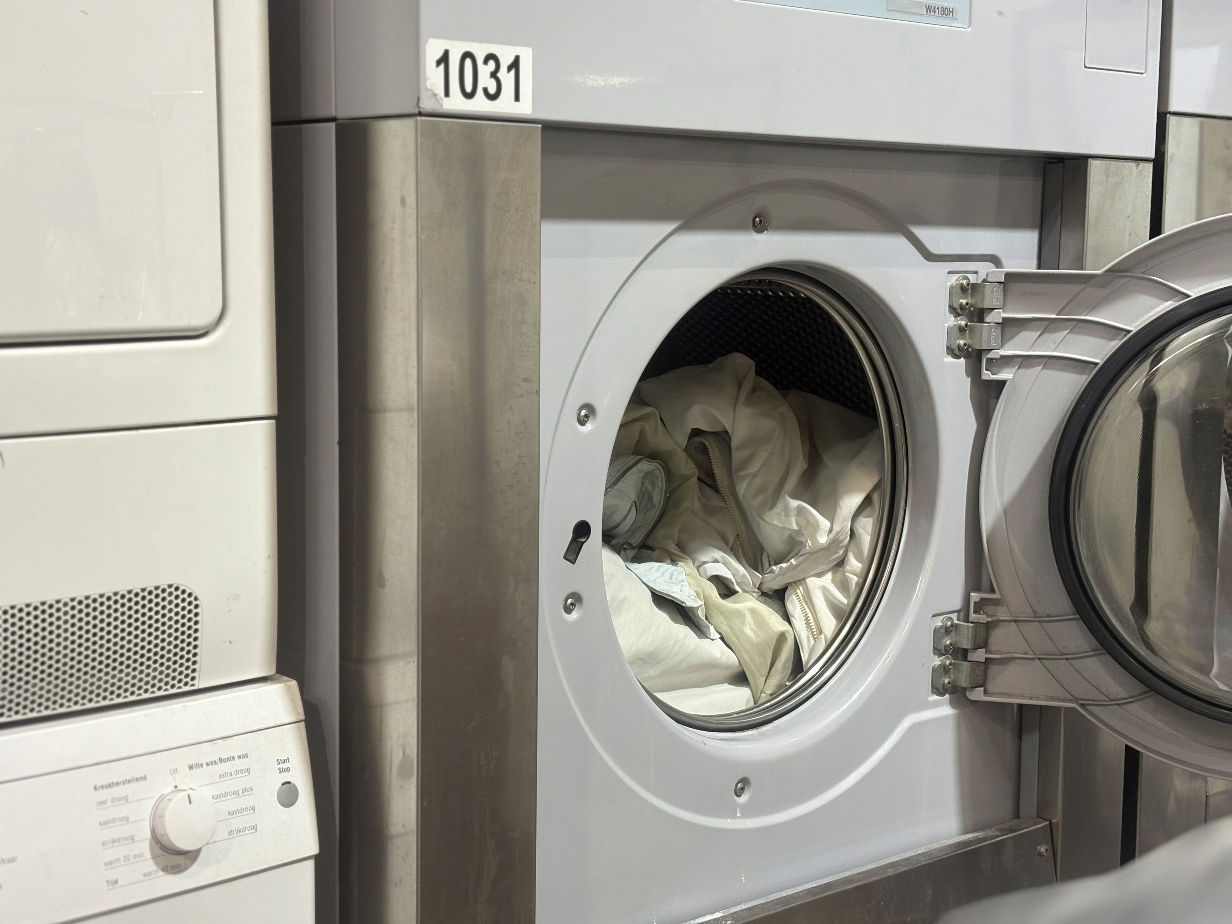 Front-loading washer with open door revealing clothes inside, next to a dryer.