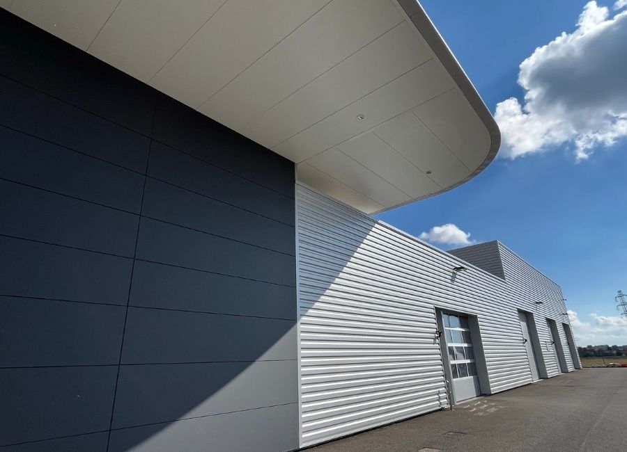 Zoom sur bardage métallique gris avec lignes ondulées et débord de toiture contemporaine.